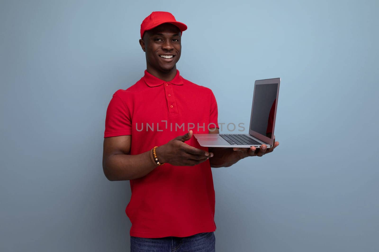 clothing for identity and branding. young handsome american man in red t-shirt and cap working in laptop repair service center.