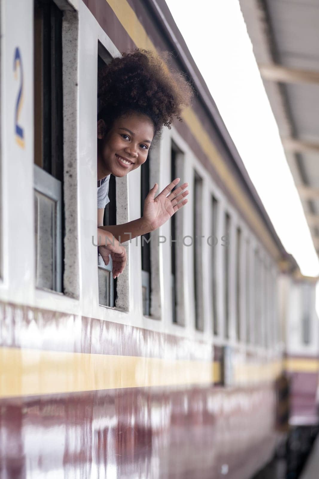 Young asian travel by train sticking her head out of the train, Happy smiling woman female girl looks out from train window travelling by train. High quality photo