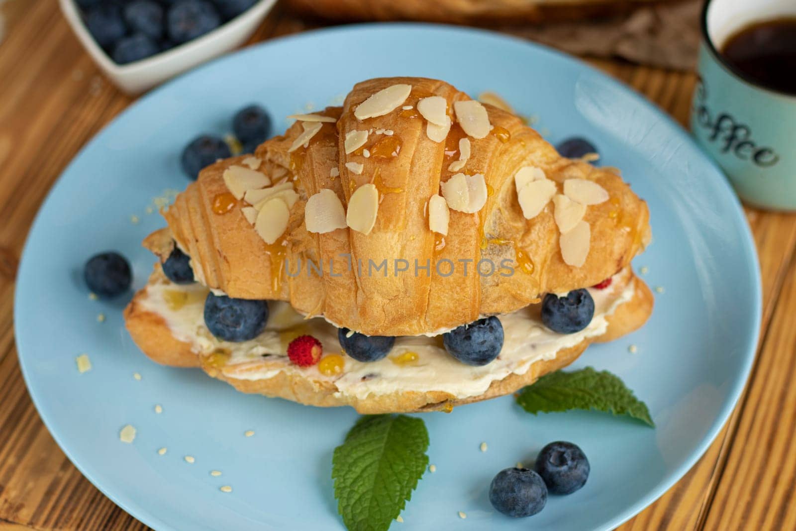 Croissant sandwich with cheese , arugula and berries. classic american breakfast. french croissant with fresh berries. blueberry strawberry on cream cheese. Croissant and cup coffee. aesthetic dessert