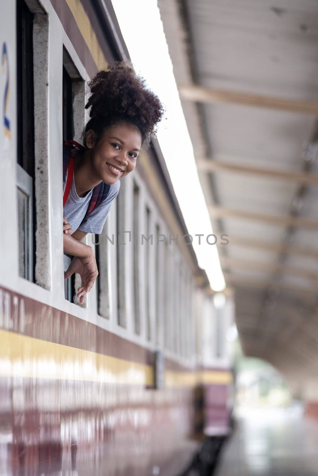 Young asian travel by train sticking her head out of the train, Happy smiling woman female girl looks out from train by wuttichaicci