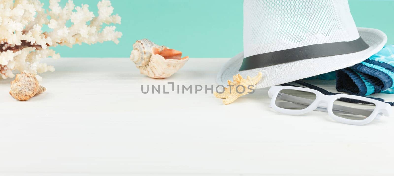 Beach hat with sunglasses and shorts on white wooden background. Summer vacation concept. Starfish and seashells.