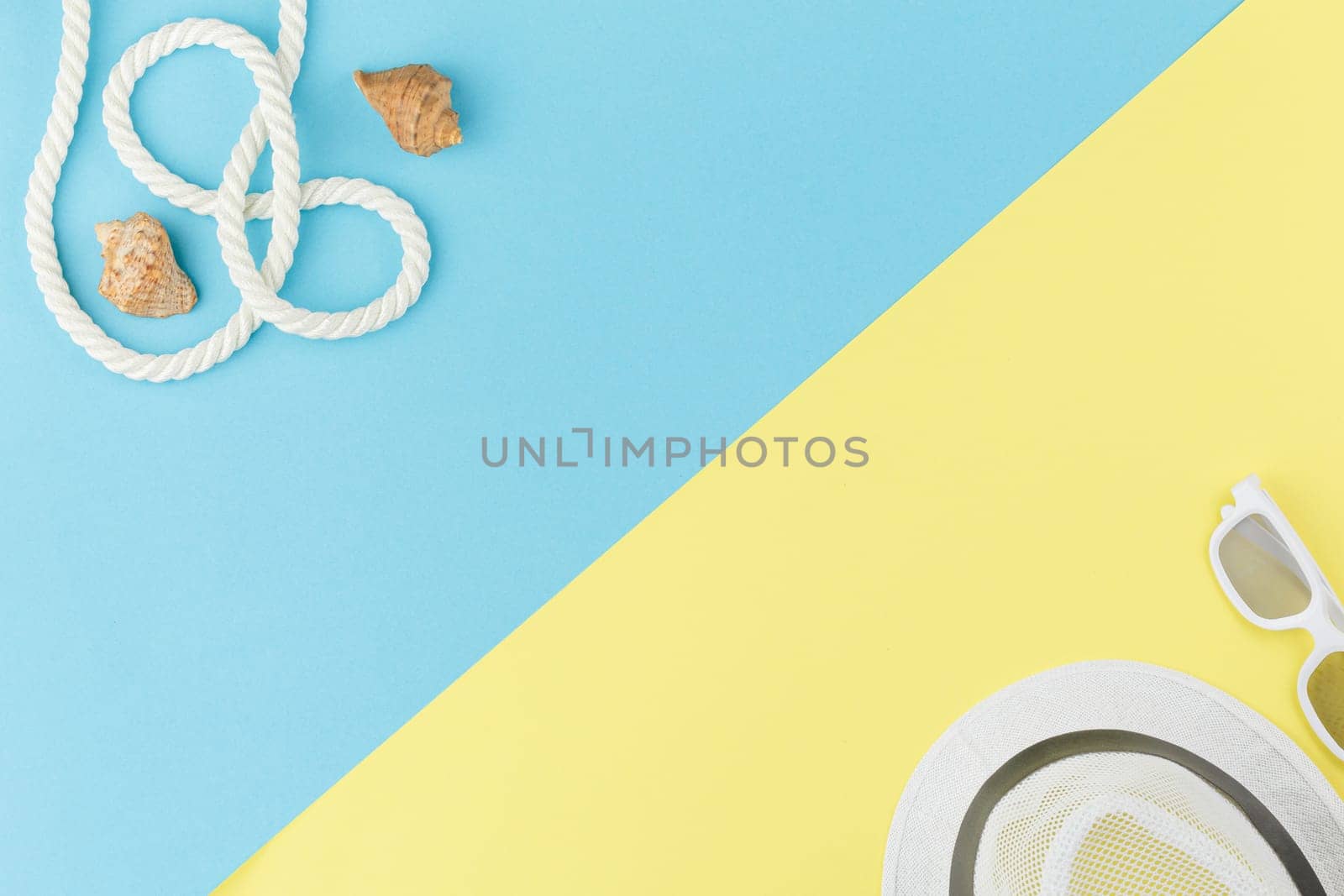 Beach hat with sunglases. Summer time. Seashells with rope on a colored background with copy space. Sea vacation concept. Top view.
