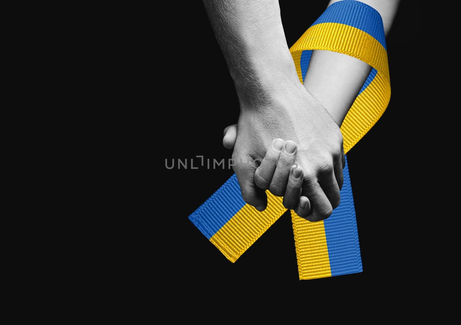 male hands hold childrens on a dark background. black and white color. with yellow and blue ribbon. concept needs help and support, truth will win
