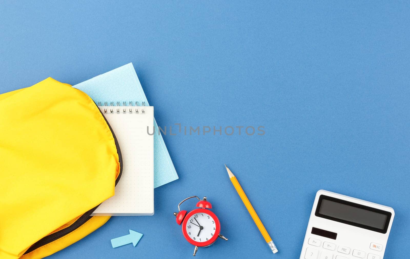 Back to school concept. Backpack with school supplies on blue isolated background. Flat lay.