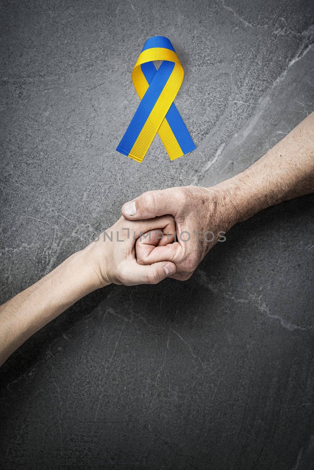 hand holding tight hand of child with yellow and blue ribbon on marble. concept needs help and support, truth will win