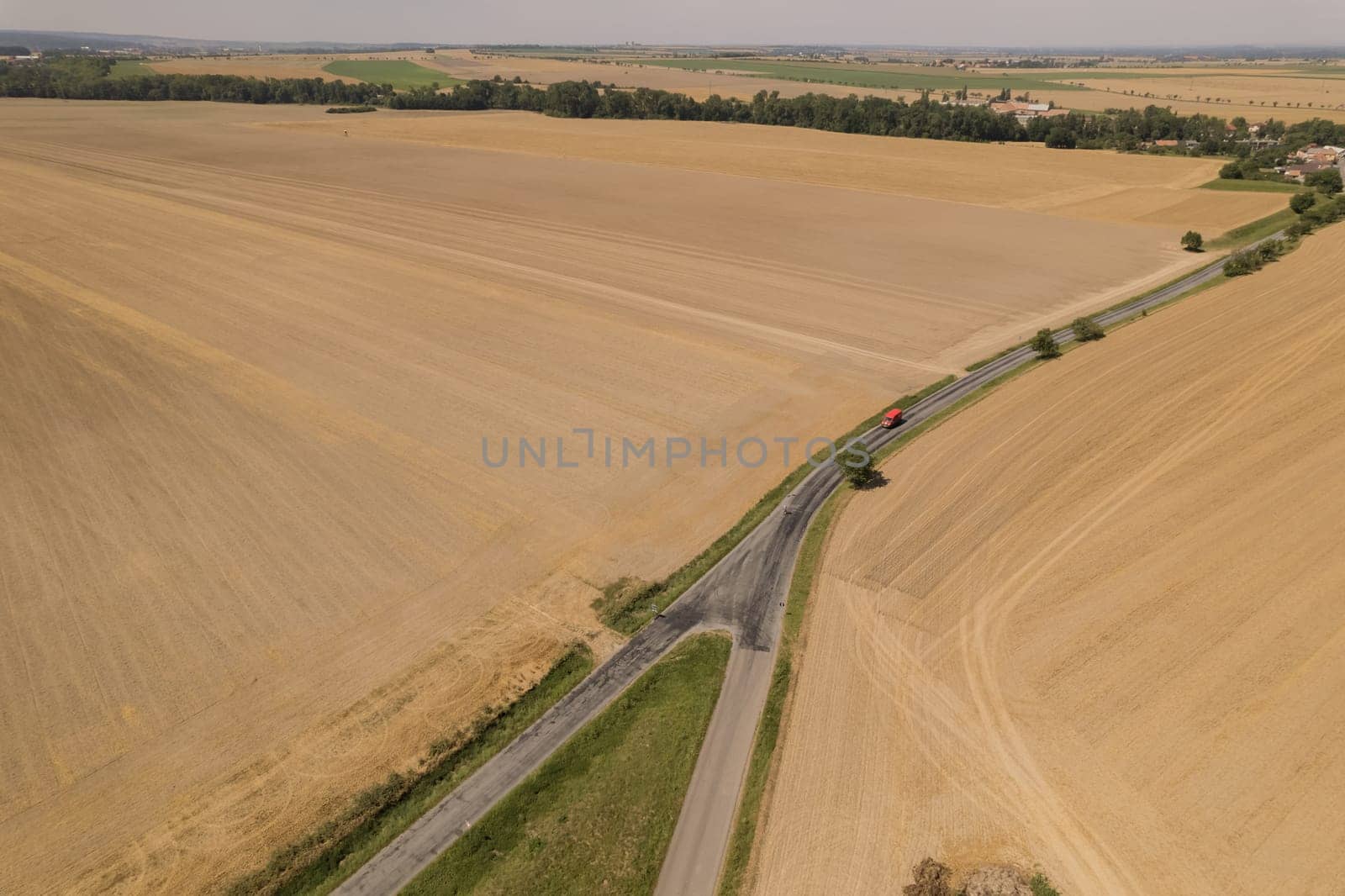 View from top of fields from which wheat is harvested, road between fields for passage of combine harvesters and tractors.