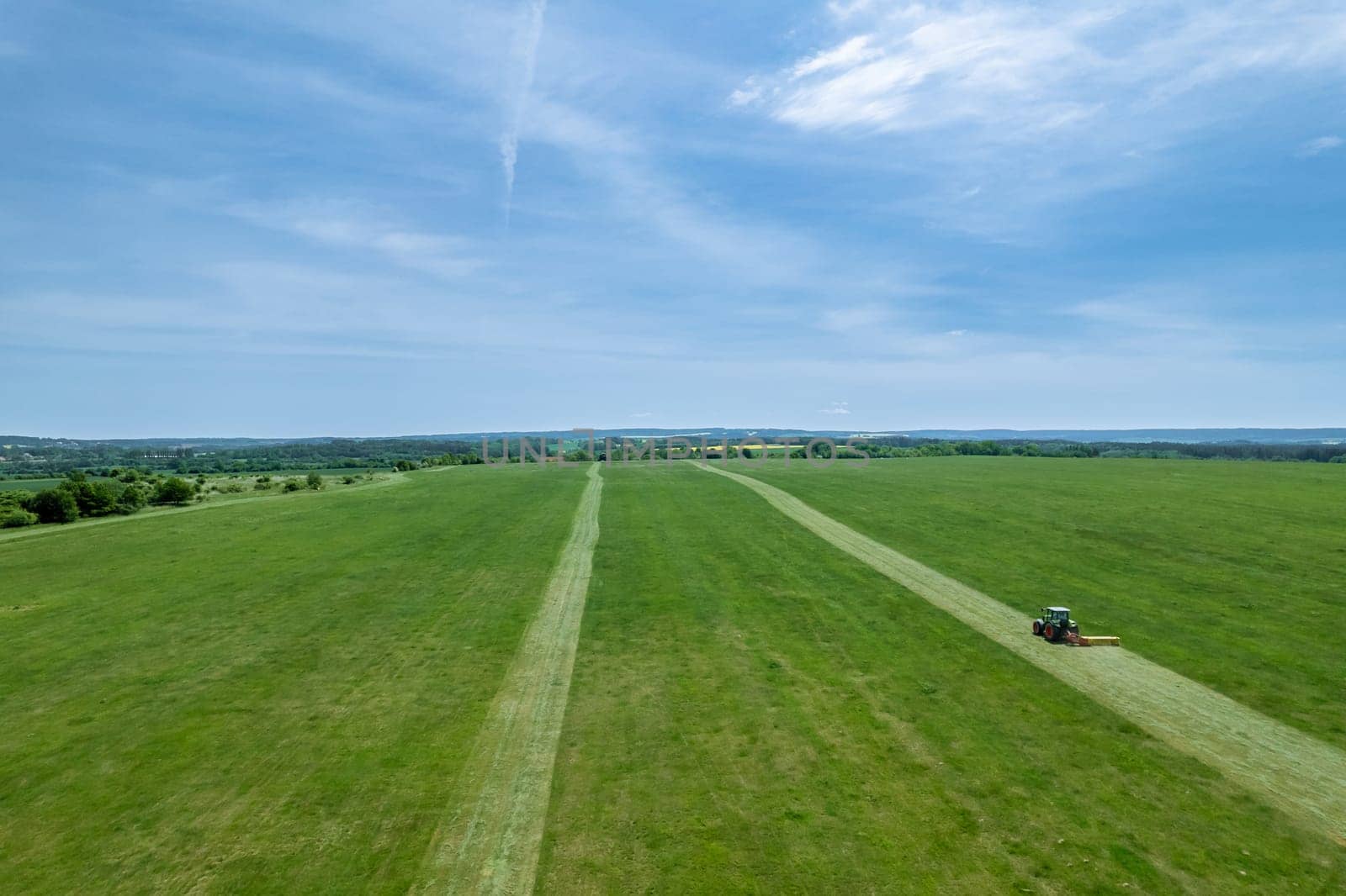 Grass is being evenly cut by tractor's rotary cutting implement. Tractor's rotary cutter makes quick work of mowing grass.