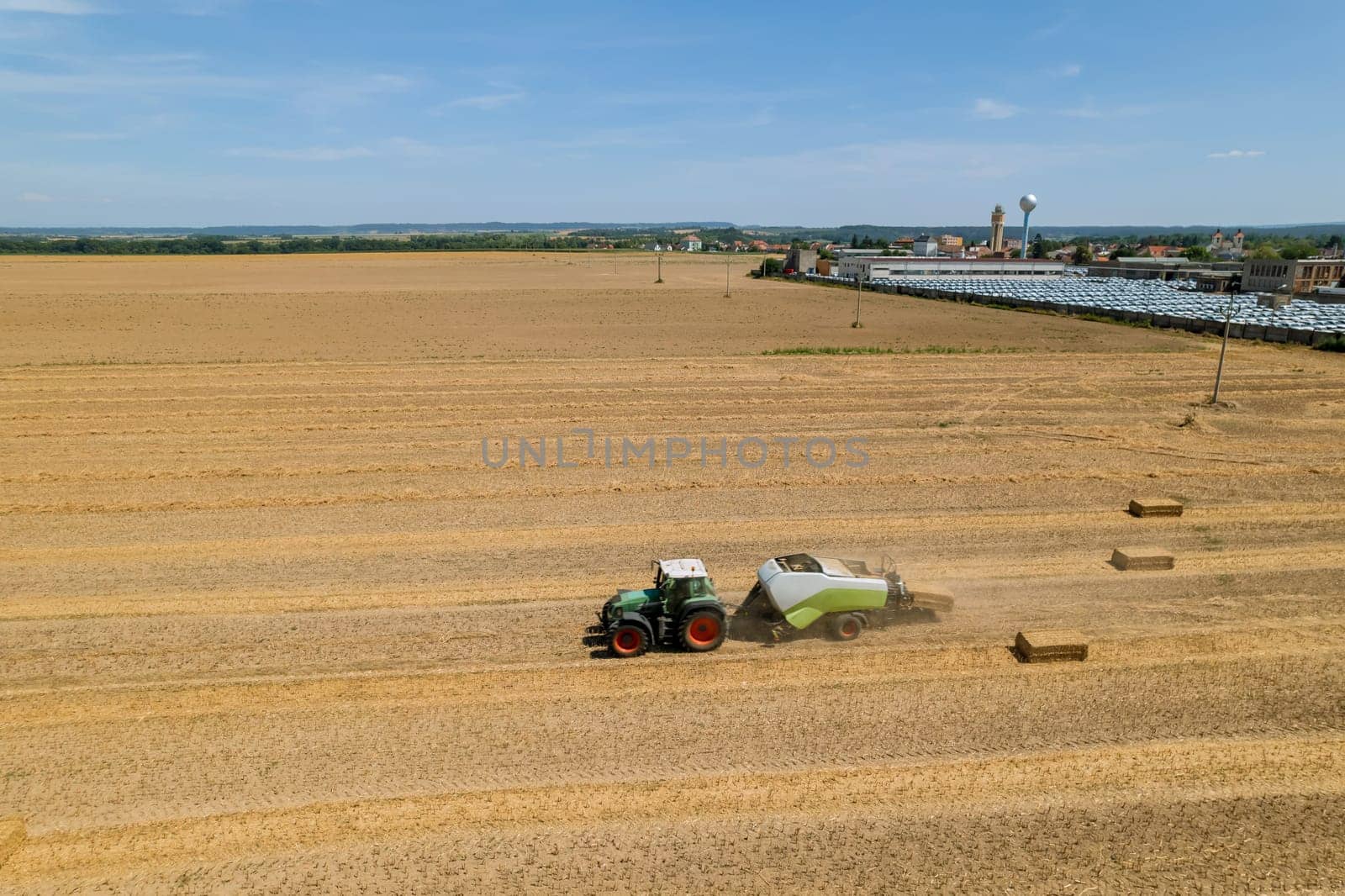 Straw is baled and loaded onto trucks for delivery to storage facility. Farmers use straw as a mulching material to protect crops from weeds and retain moisture.