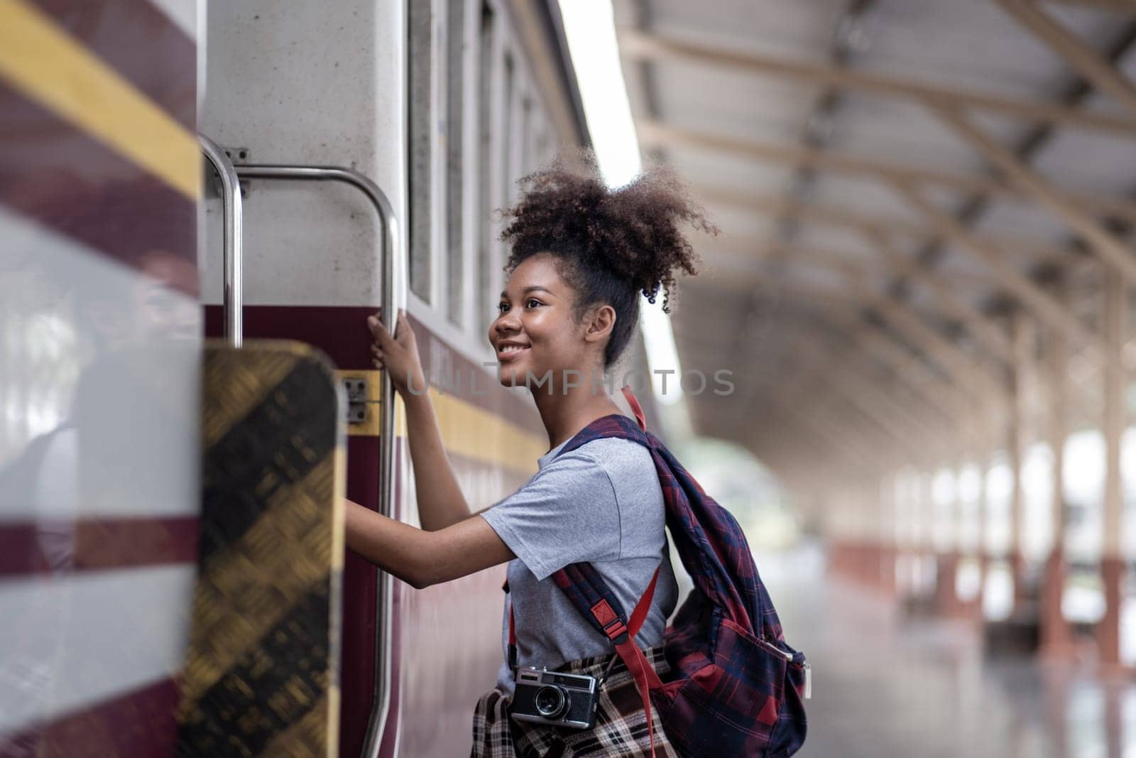 Traveler African Asian American woman getting in a train to hop on train, Young woman female standing on train door peeking out looking from door, tourist on a train station. High quality photo