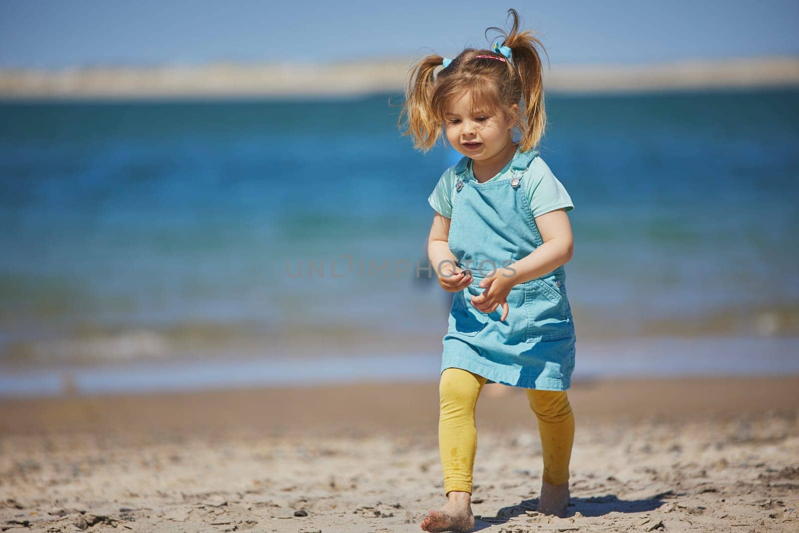 Charming child walking on the beach in Denmark.