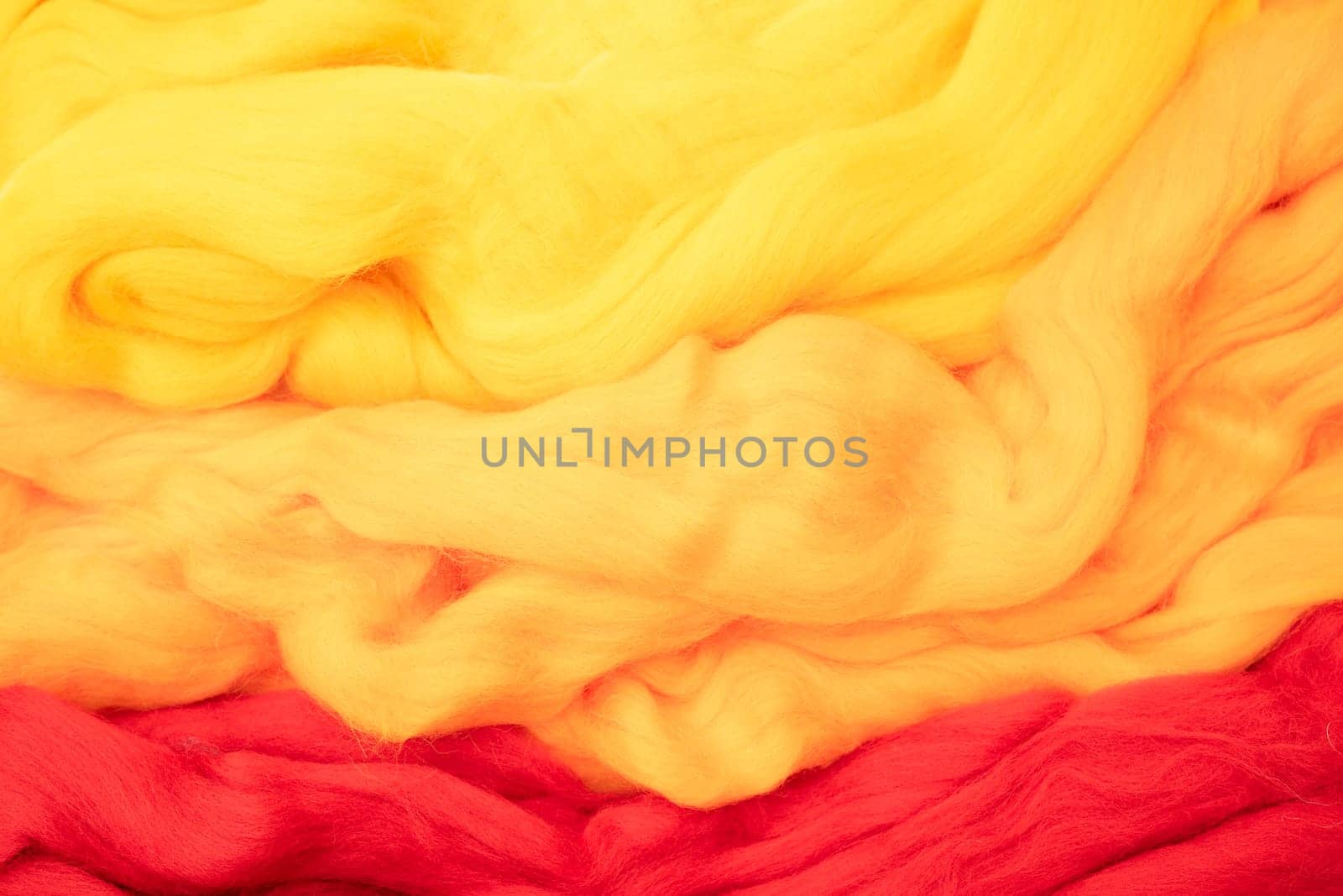 Yellow, beige and red merino wool for felting as background texture.