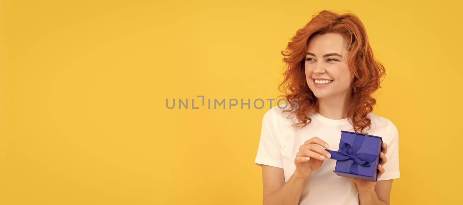 laughing woman with present box on yellow background, birthday. Woman isolated face portrait, banner with mock up copy space