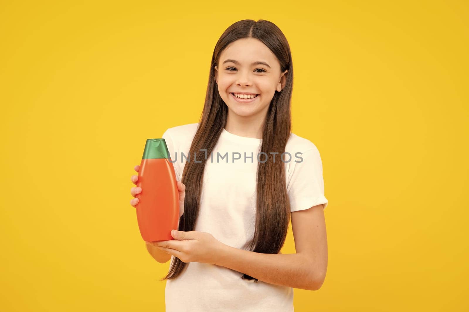 Child with shampoo conditioner. Daily cosmetic care. Teenager hold bottle of hair and skin care. Beauty health and cosmetics. Happy teenager portrait. Smiling girl. by RedFoxStudio