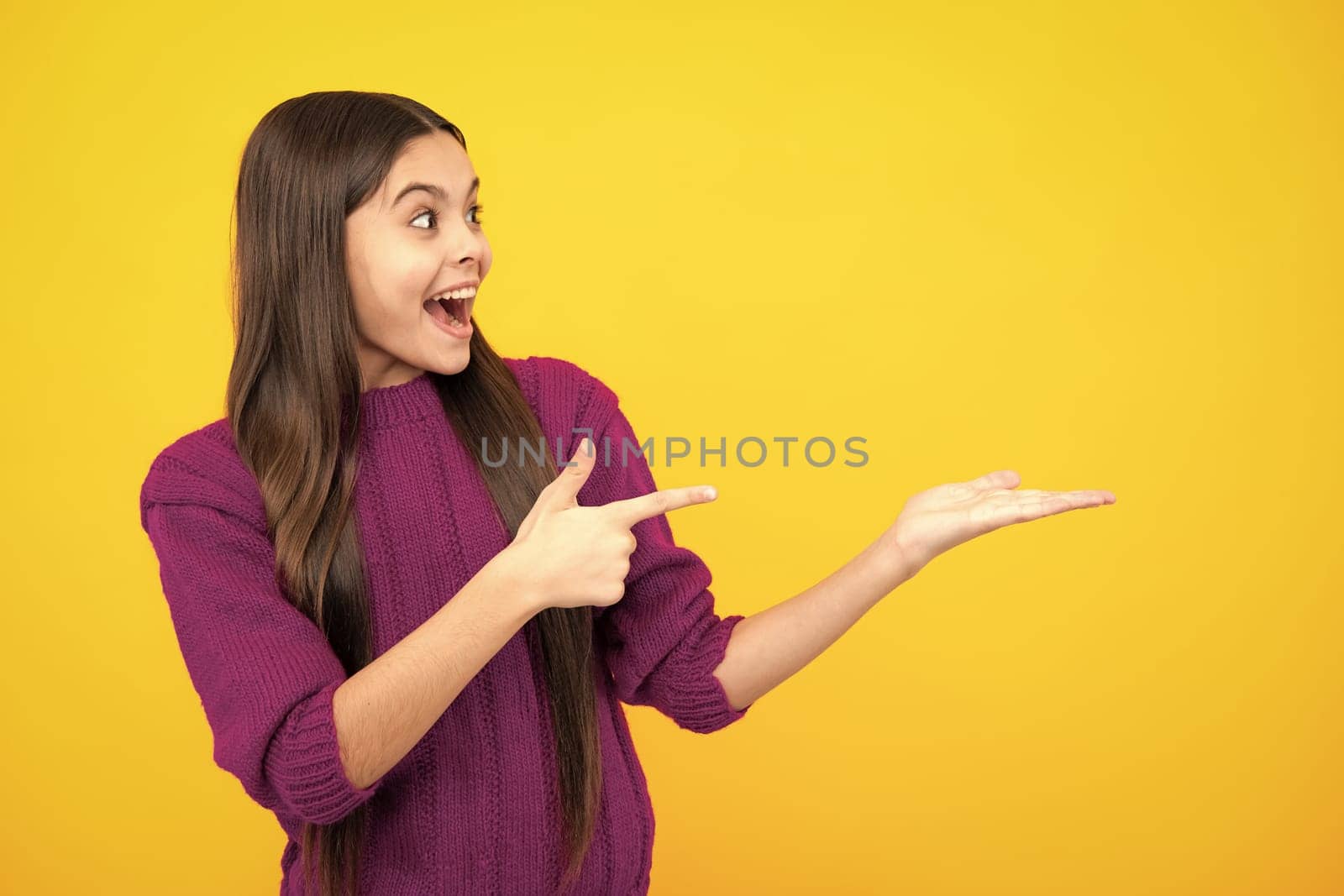 Wow, it's unbelievable. Shocked teenager child pointing aside at copy space. Teen girl pointing with two hands and fingers to the side. by RedFoxStudio