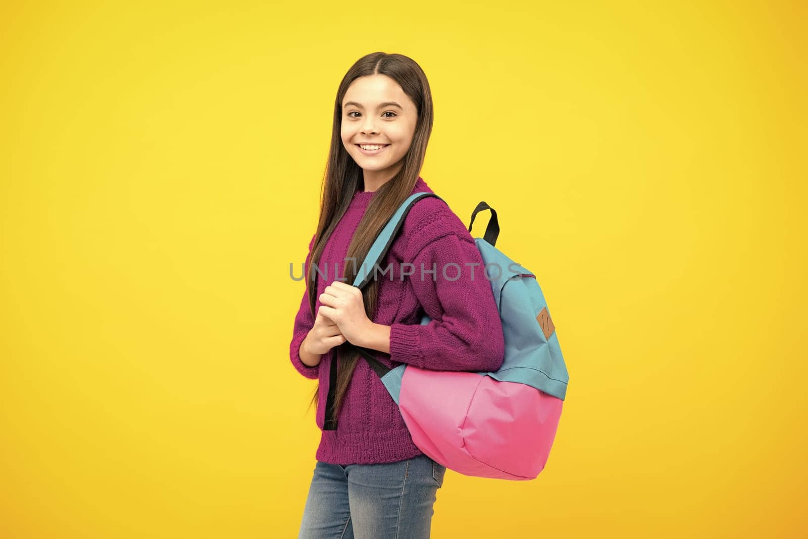 Schoolgirl in school uniform with school bag. Schoolchild, teen student hold backpack on yellow isolated background