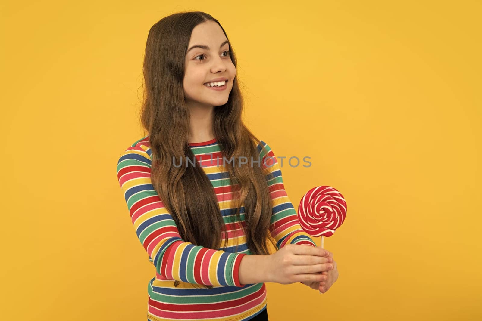 Cool teen child with lollipop over yellow isolated background. Sweet childhood life. Teen girl with yummy lollipop candy