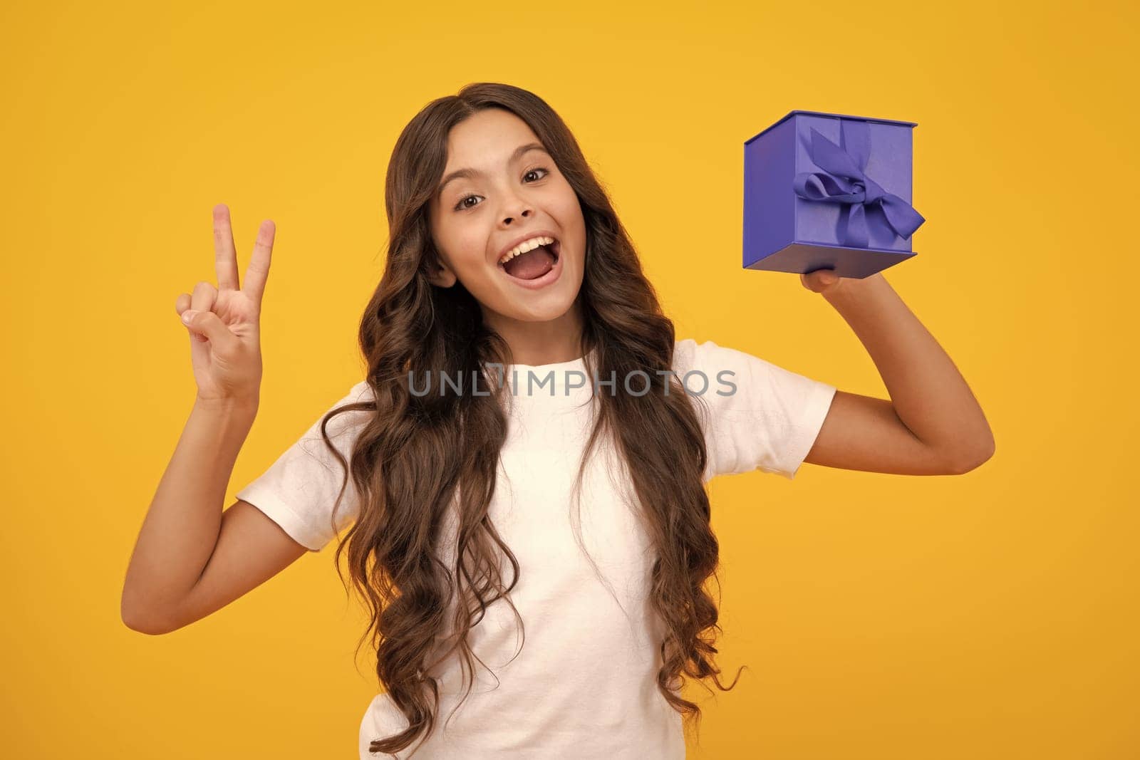 Amazed teen girl. Portrait of teenager child girl 12, 13, 14, years old holding Christmas gift box. Teen giving birthday gift. Excited expression, cheerful and glad. by RedFoxStudio