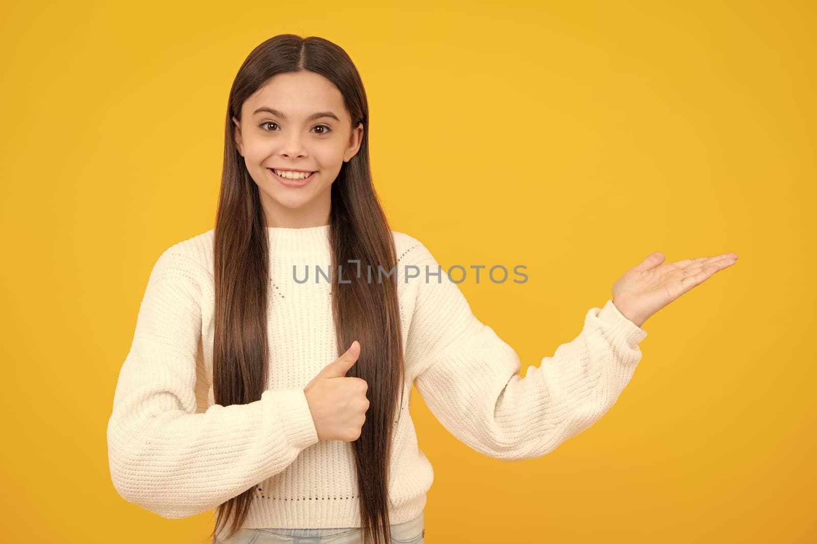 Wow, it's unbelievable. Shocked teenager child pointing aside at copy space. Teen girl pointing with two hands and fingers to the side. by RedFoxStudio