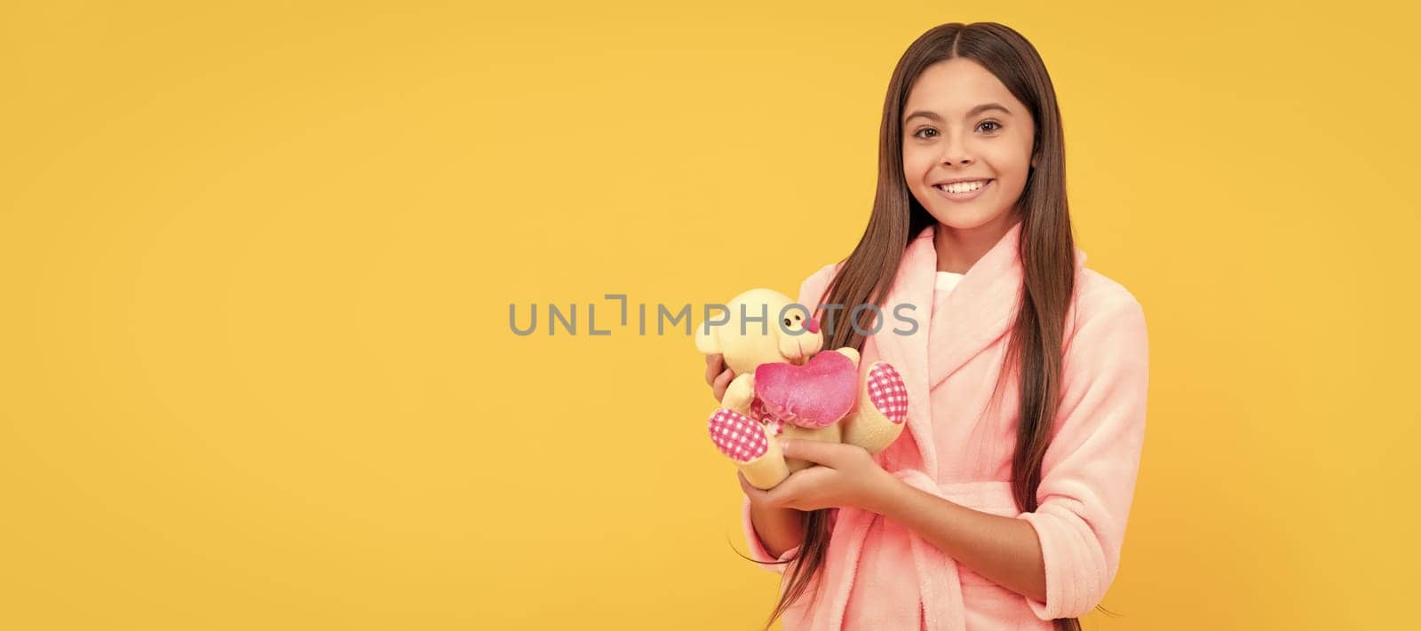 happy teen girl in home terry bathrobe with toy, happiness. Banner of child girl with toy, studio portrait, header with copy space