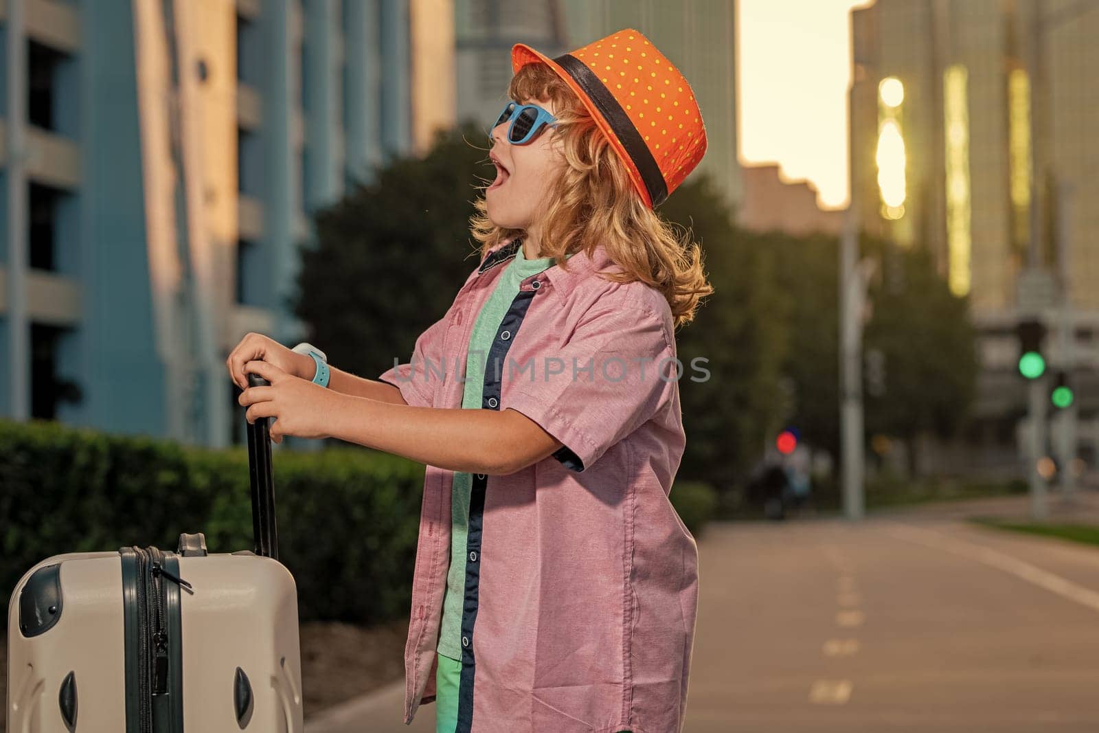 Portrait of happy child traveler with luggage. Positive little tourist with suitcase ready to travelling. Happy kid tourist with baggage going to travel on holidays