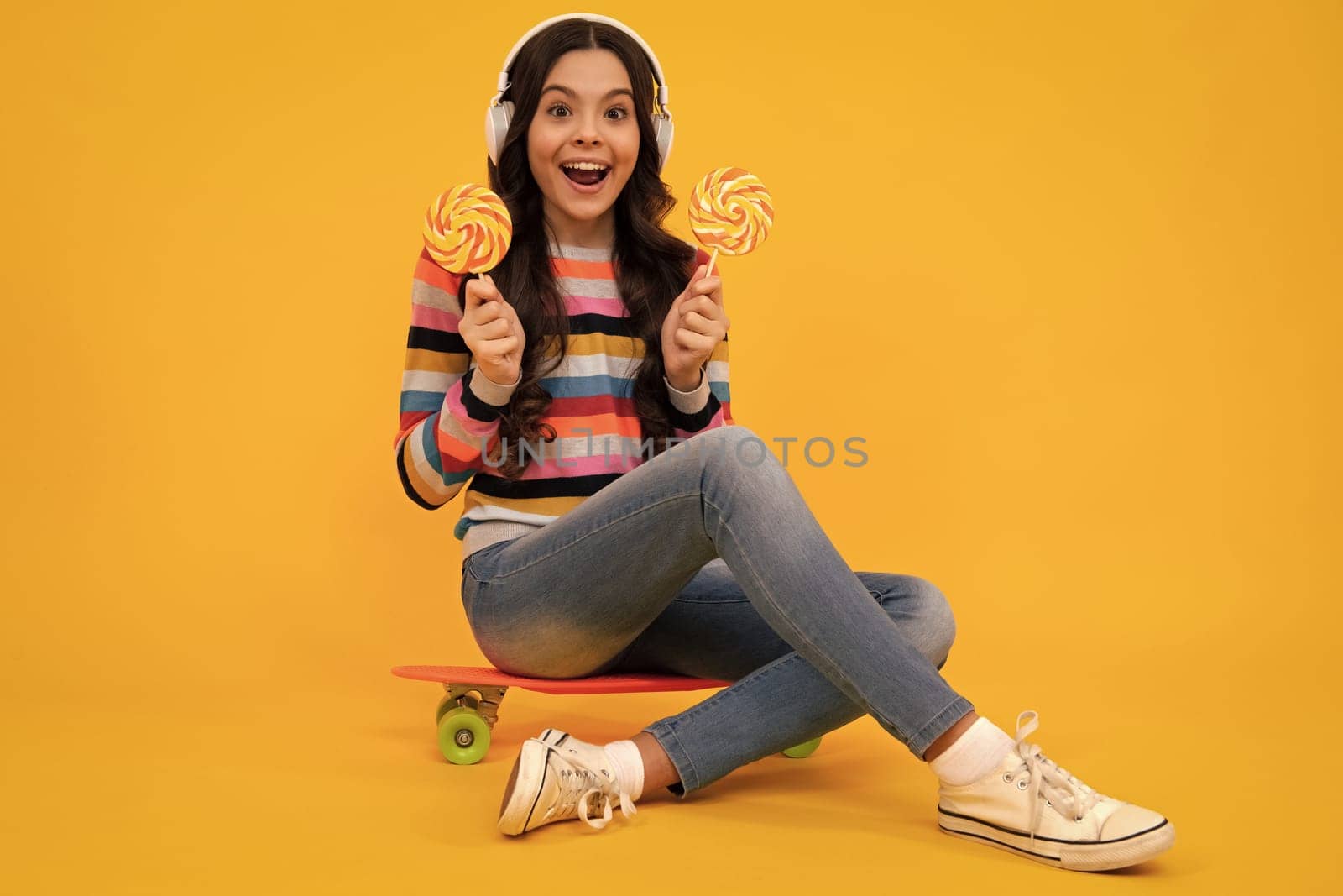 Amazed teenager. Teen girl hold lollipop caramel on yellow background, candy shop. Teenager with sweets suckers. Excited teen girl