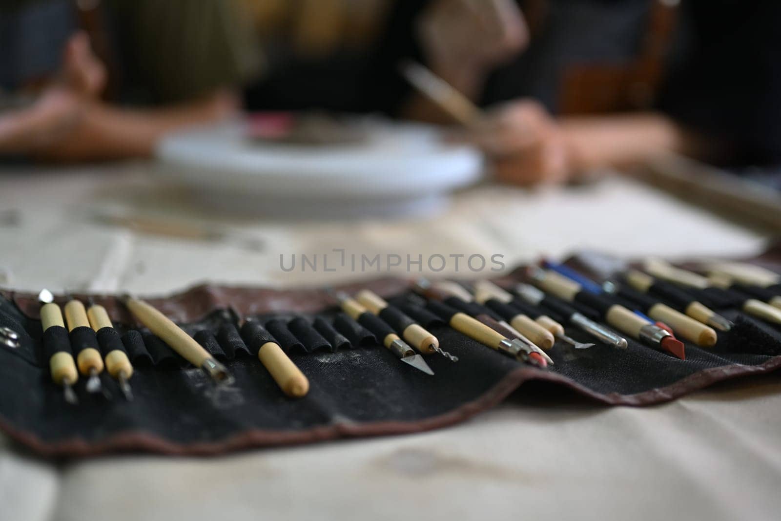 Closeup shot of various tools for pottery on table in workshop. Handicraft, creativity, hobby and activity concept by prathanchorruangsak