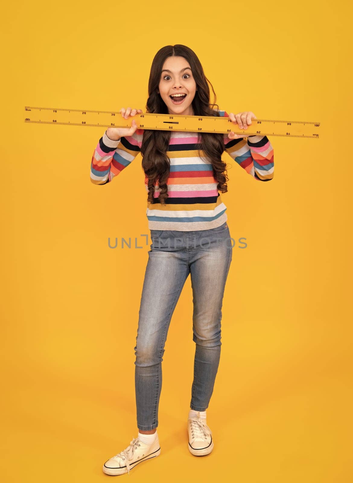 Amazed teenager. Back to school. School girl hold ruler measuring isolated on yellow background. Excited teen schoolgirl