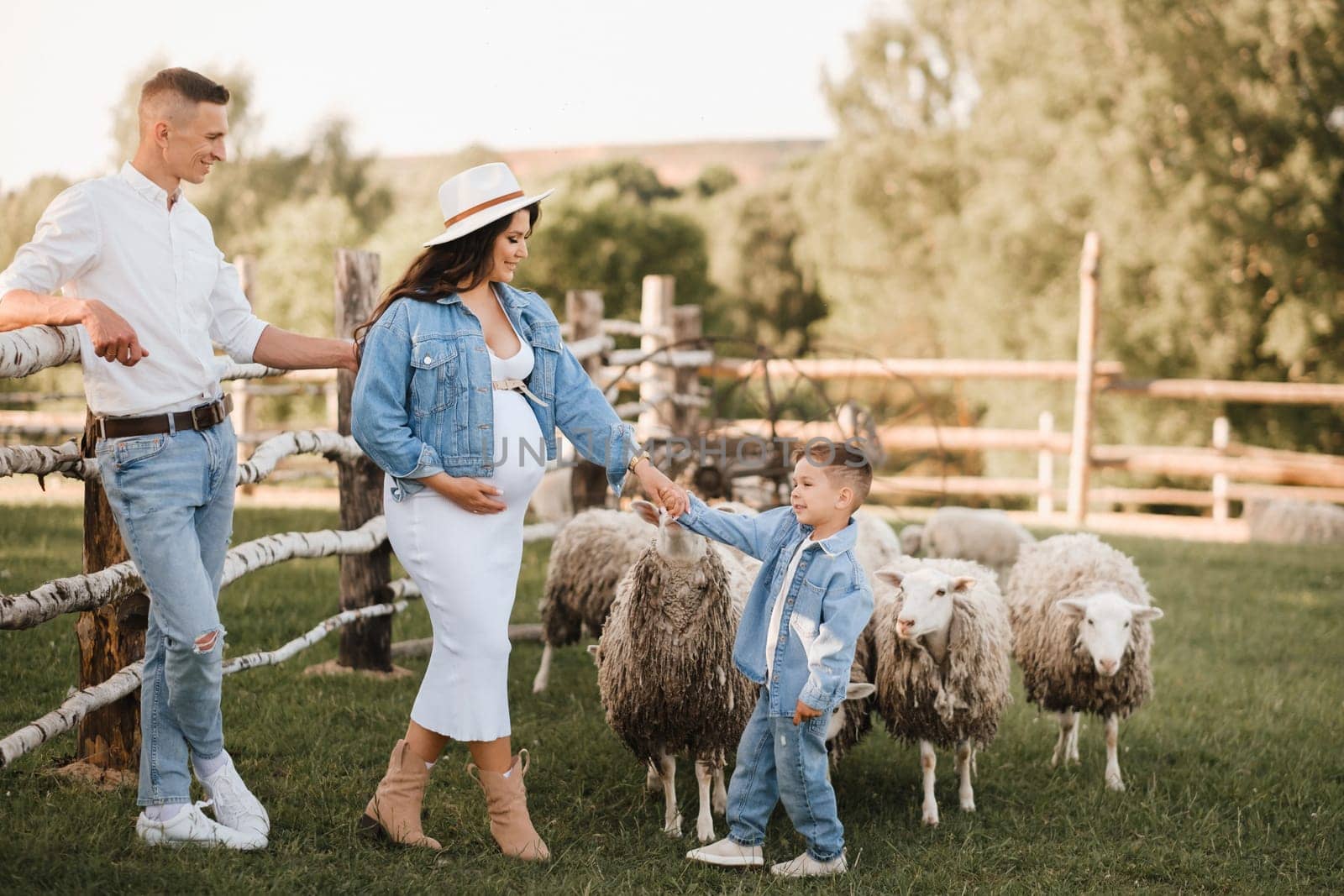 Stylish family in summer on a village farm with sheep by Lobachad
