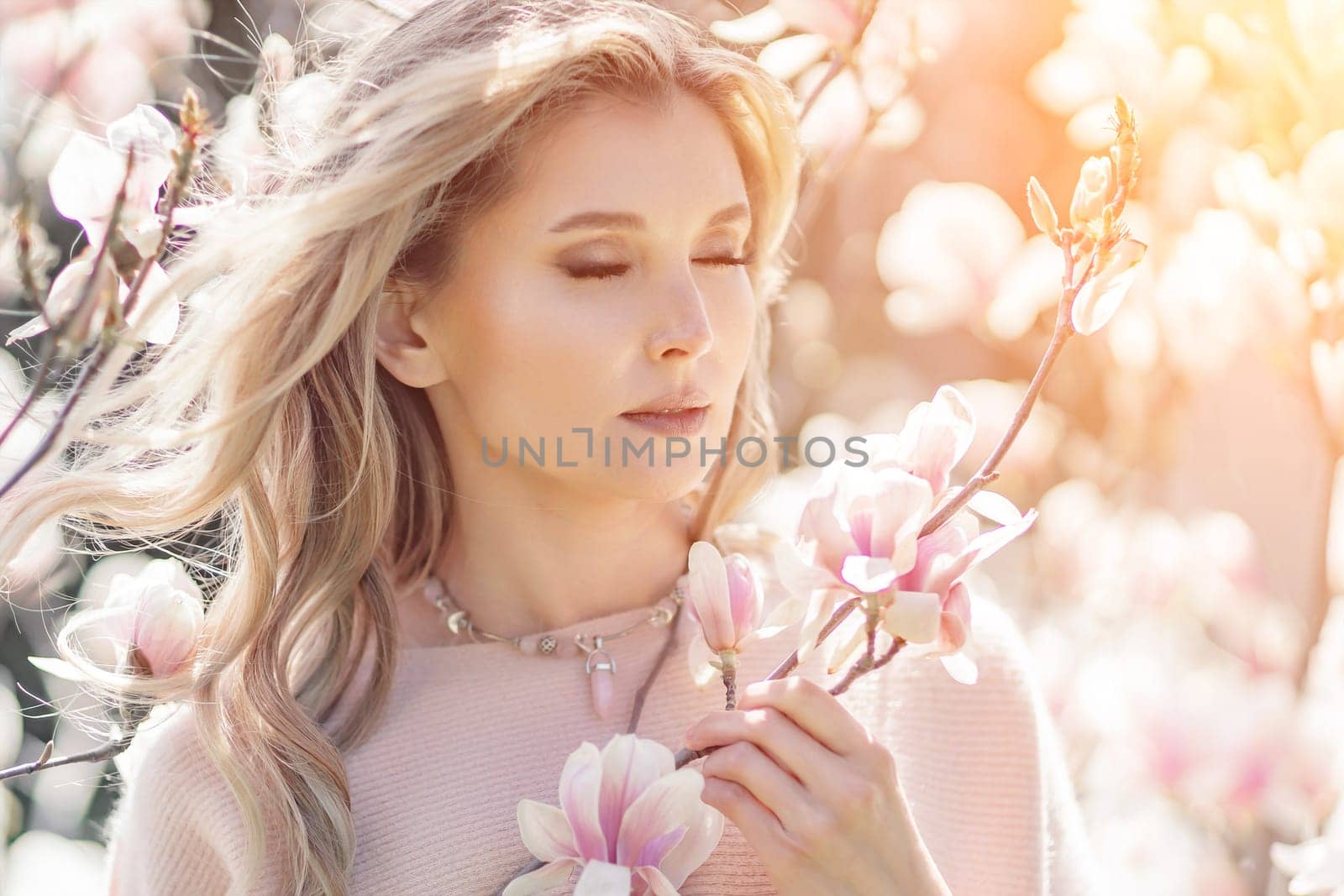Magnolia woman portrait. Happy middle aged woman enjoying the smell in a blooming spring garden. Beautiful magnolia bushes, large flowers