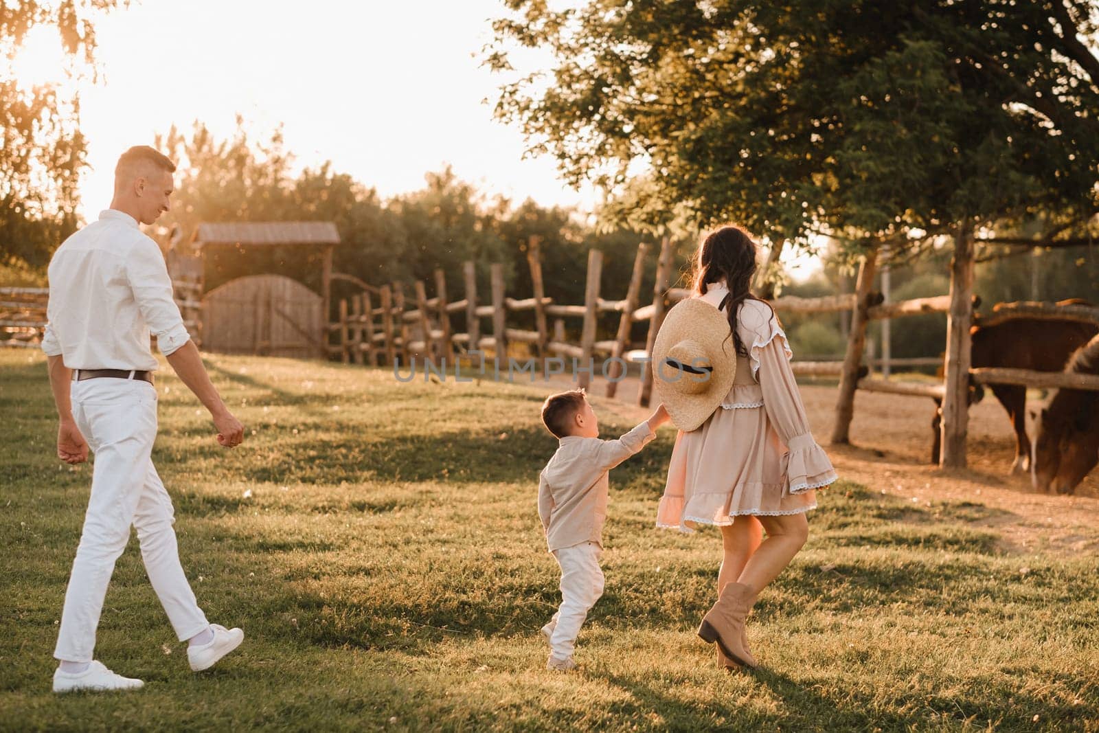 A stylish family in the countryside at sunset. A pregnant woman with her husband and son in nature by Lobachad