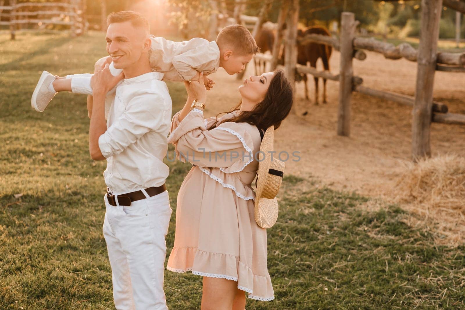 A stylish family in the countryside at sunset. A pregnant woman with her husband and son in nature by Lobachad