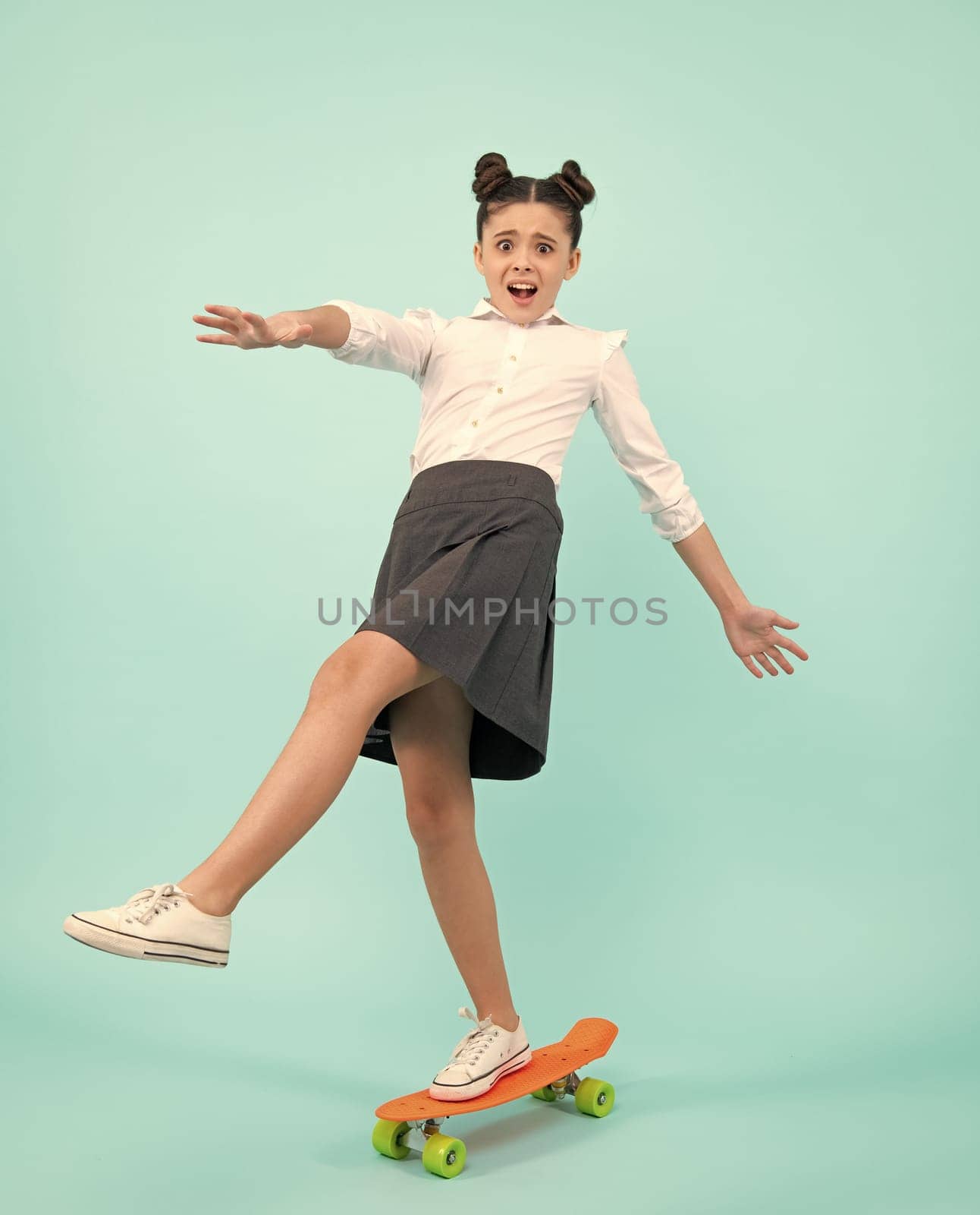 Funny face. Teenagers youth casual culture. Teen girl with skateboard over isolated studio background. Teenager in fashion stylish clothes