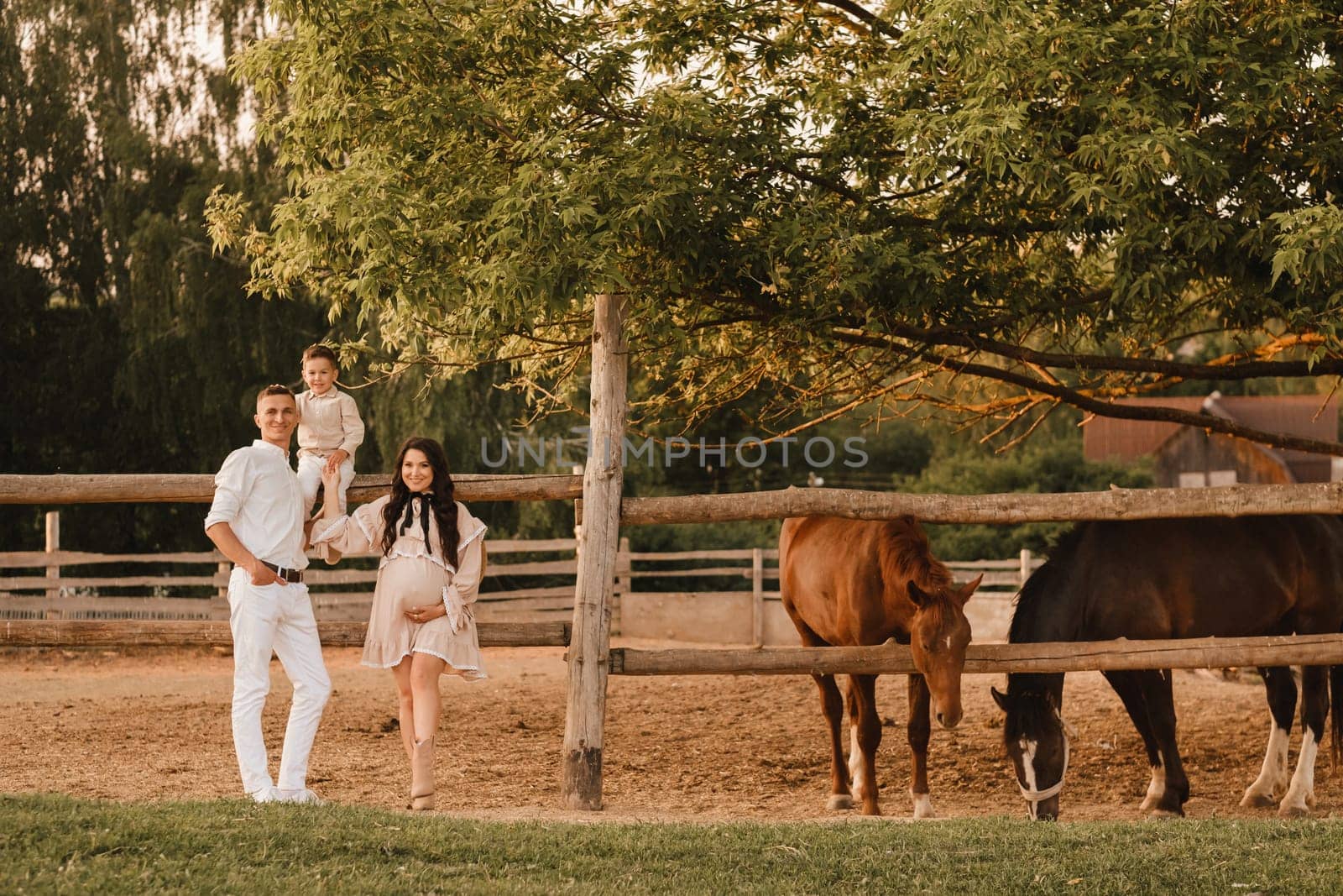 Happy family near horses at a farmer's ranch at sunset.