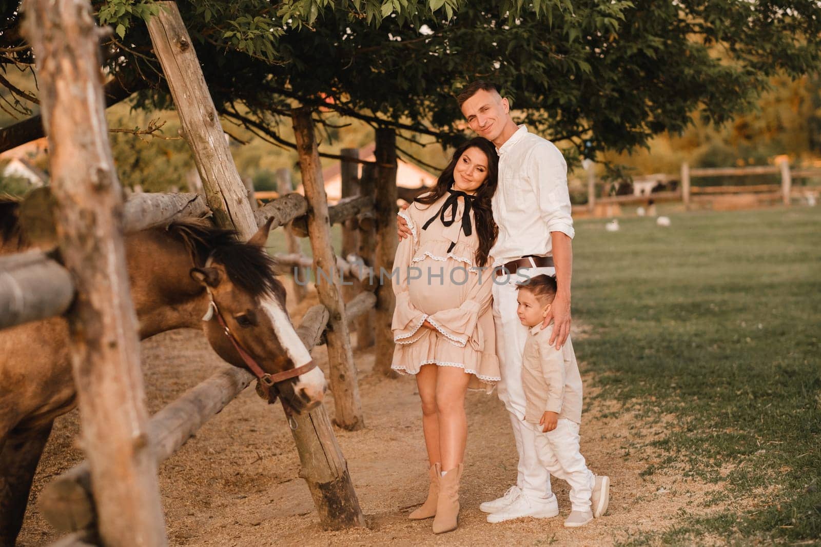 Happy family near horses at a farmer's ranch at sunset.