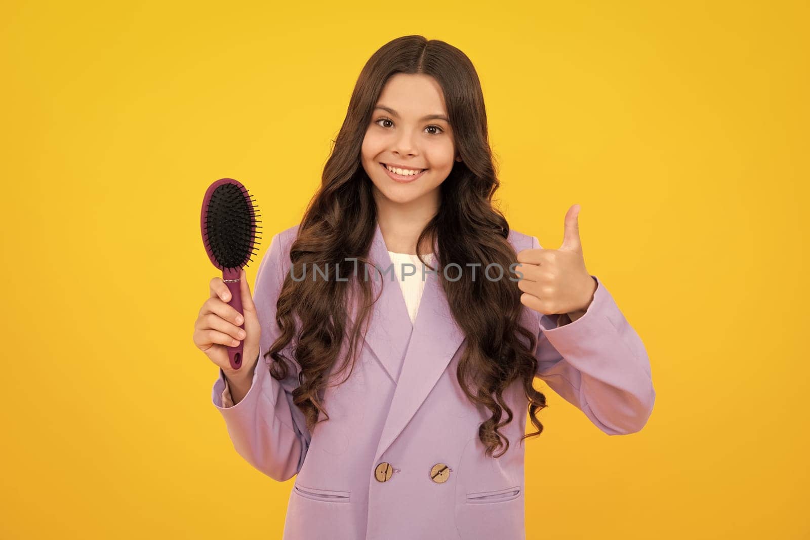 Teenager girl with long hair holding comb hairbrush for combing, beauty. Conditioner shampoo hair. Beauty kids salon. Child hairstyle. Happy face, positive and smiling emotions.