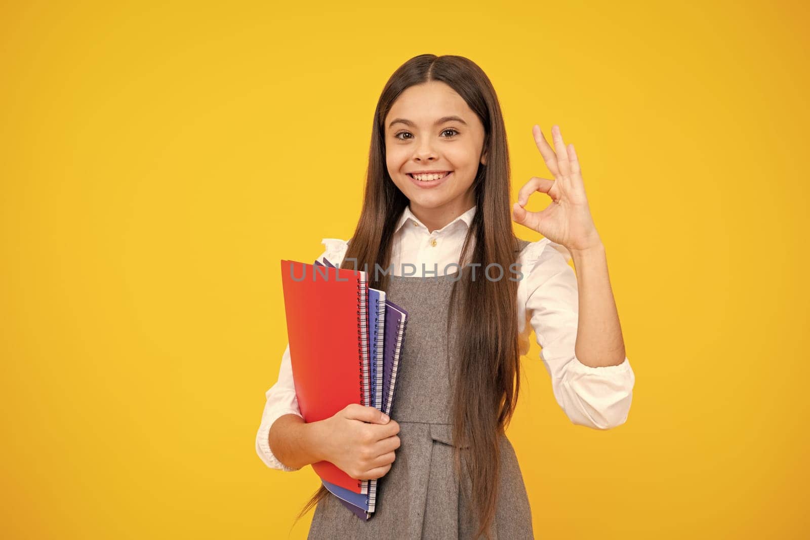 Teen girl pupil hold books, notebooks, isolated on yellow background, copy space. Back to school, teenage lifestyle, education and knowledge. by RedFoxStudio