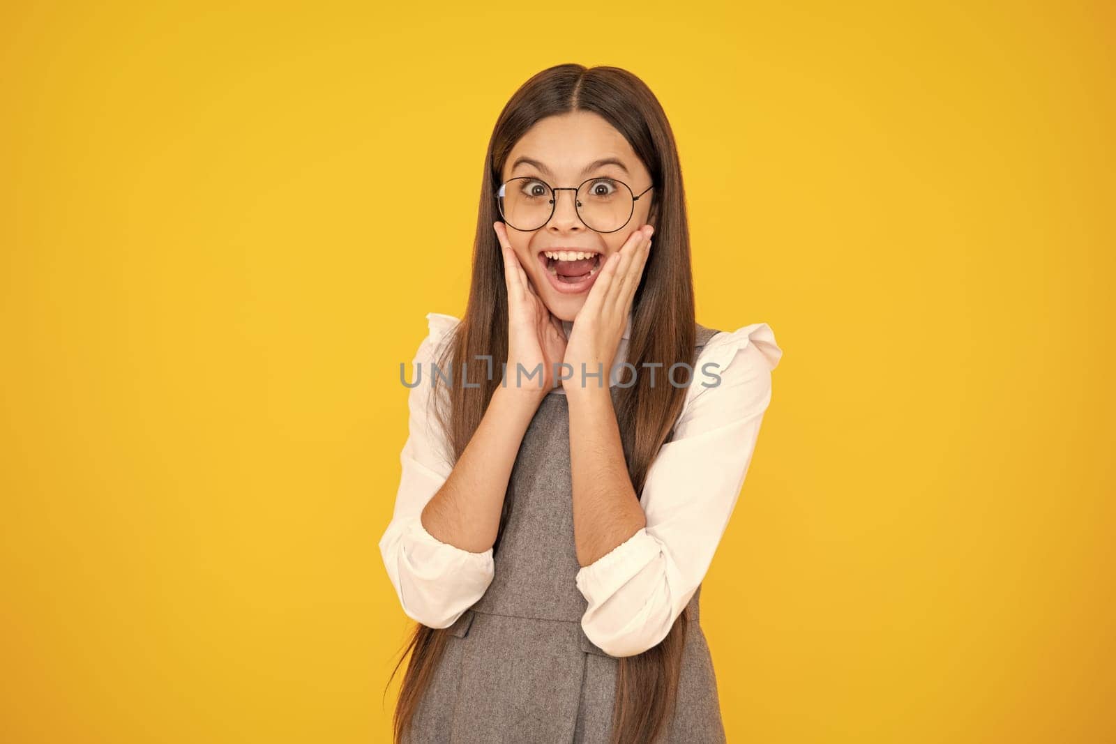 Shocked teenager child girl portrait isolated on yellow background. Excited face. Amazed expression, cheerful and glad