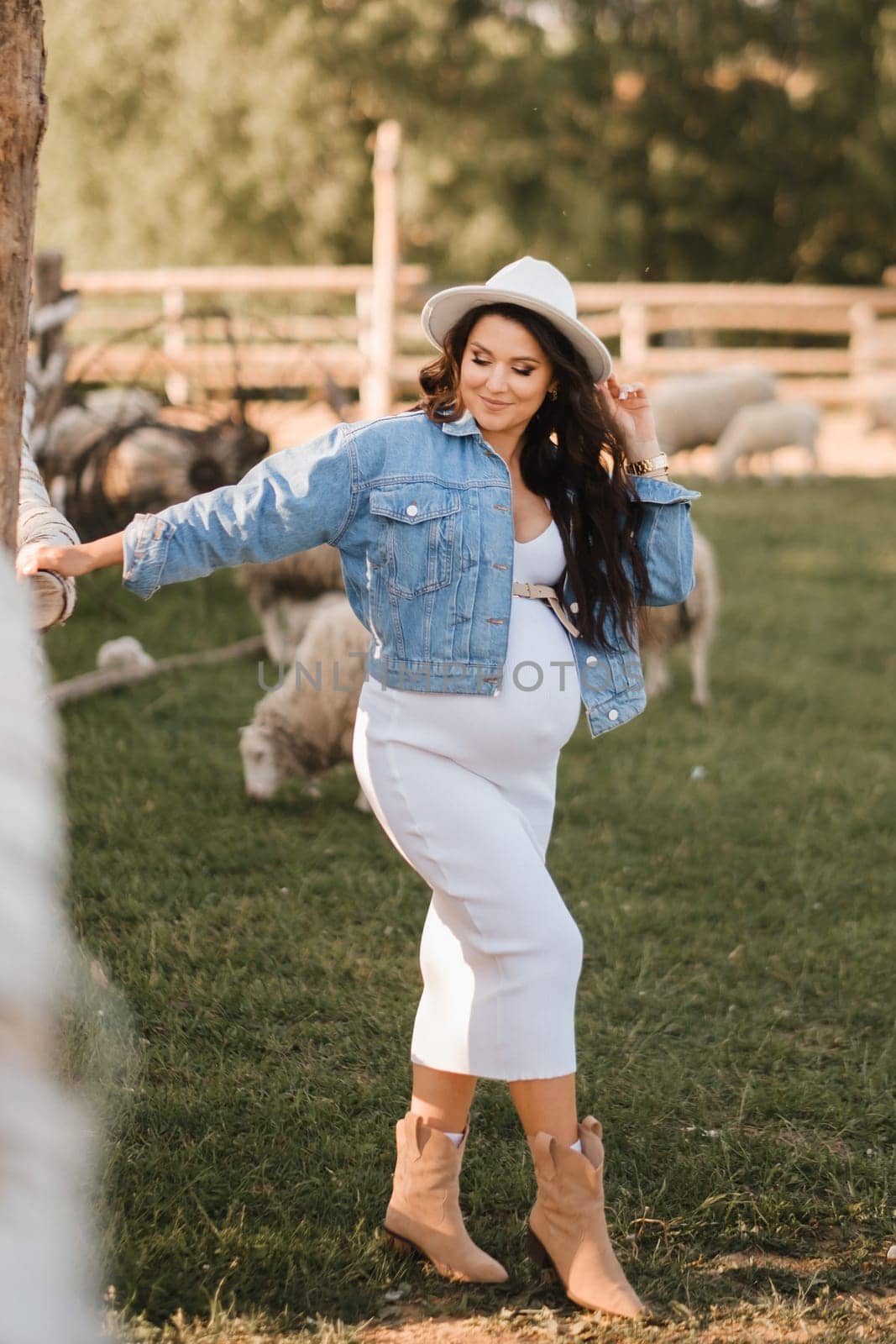 Stylish pregnant woman in a white hat in the countryside by Lobachad