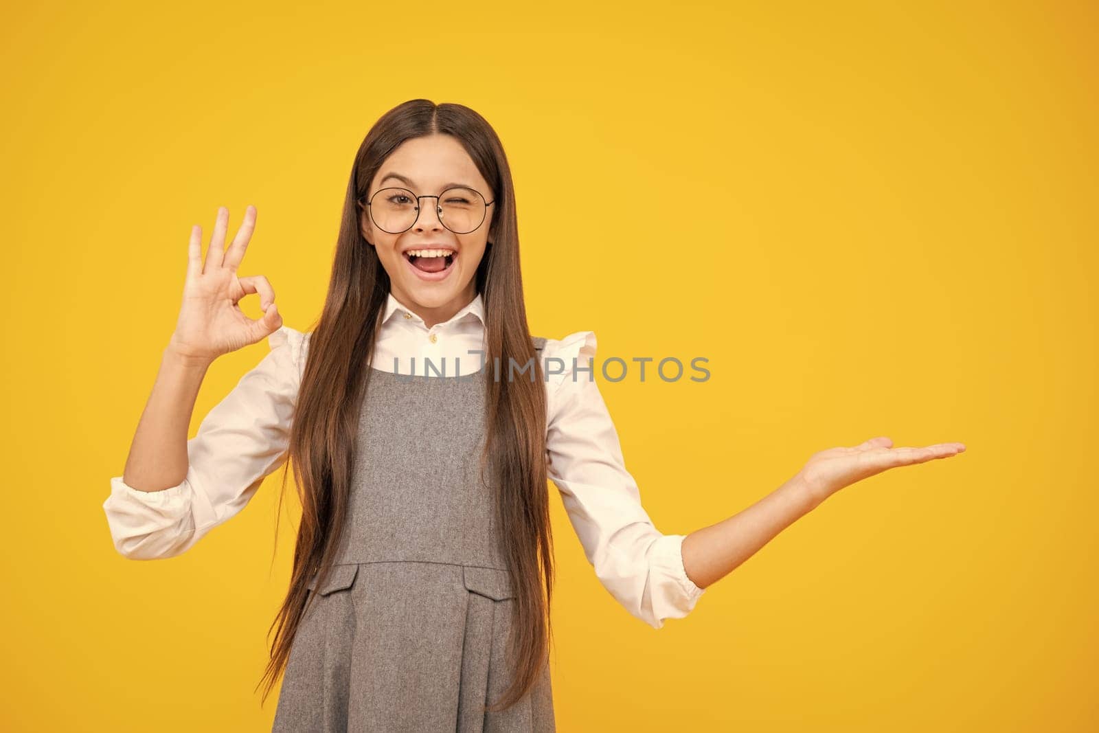 Excited face. Teenager child pointing to the side with a finger to present a product or idea. Teen girl in casual outfit pointing empty space. Amazed expression, cheerful and glad