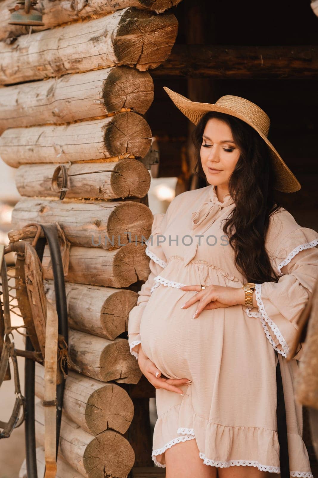 pregnant woman in a dress and hat in the countryside.