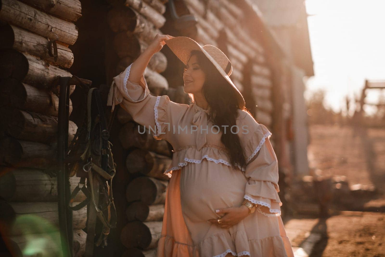 pregnant woman in a dress and hat in the countryside.