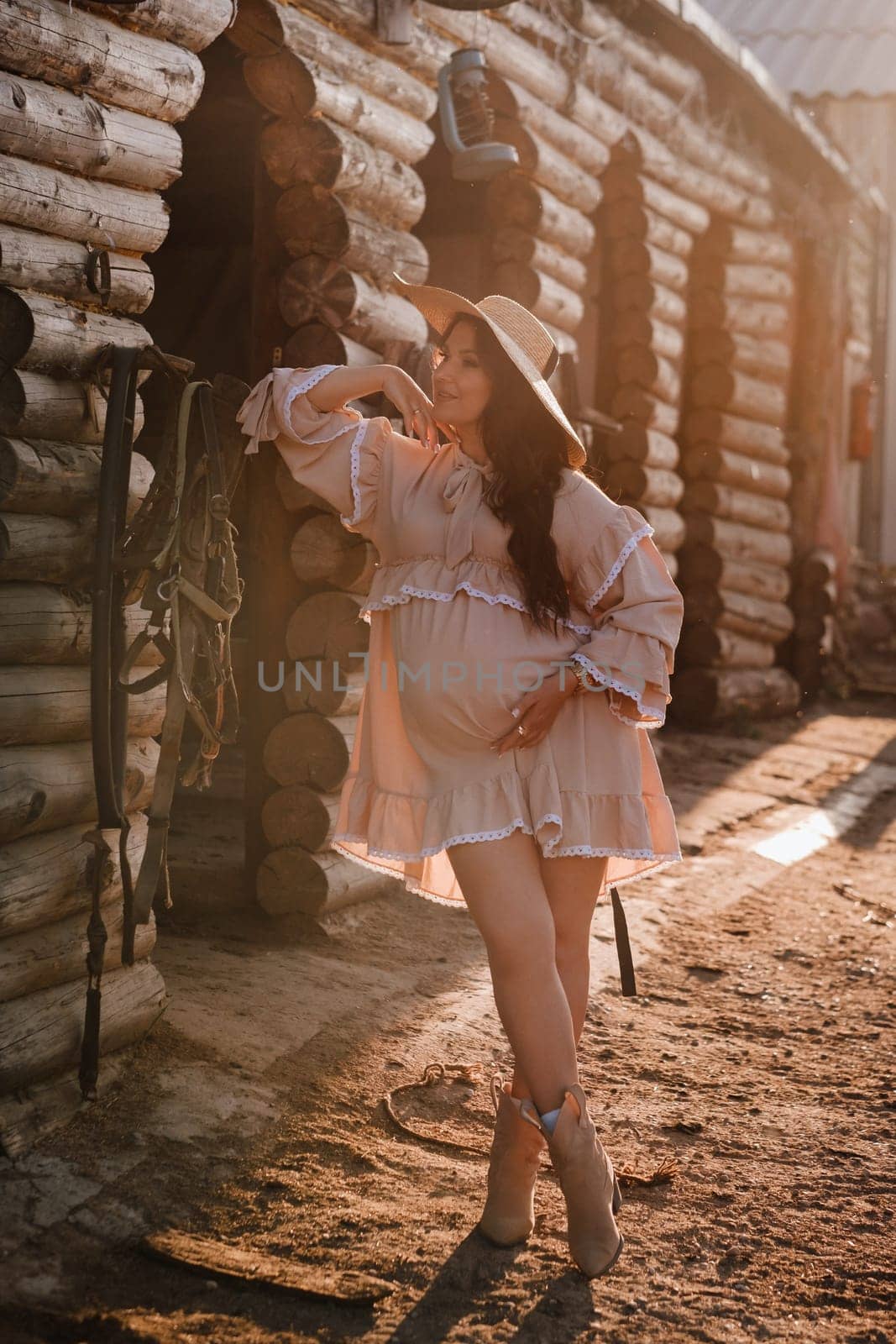 pregnant woman in a dress and hat in the countryside.