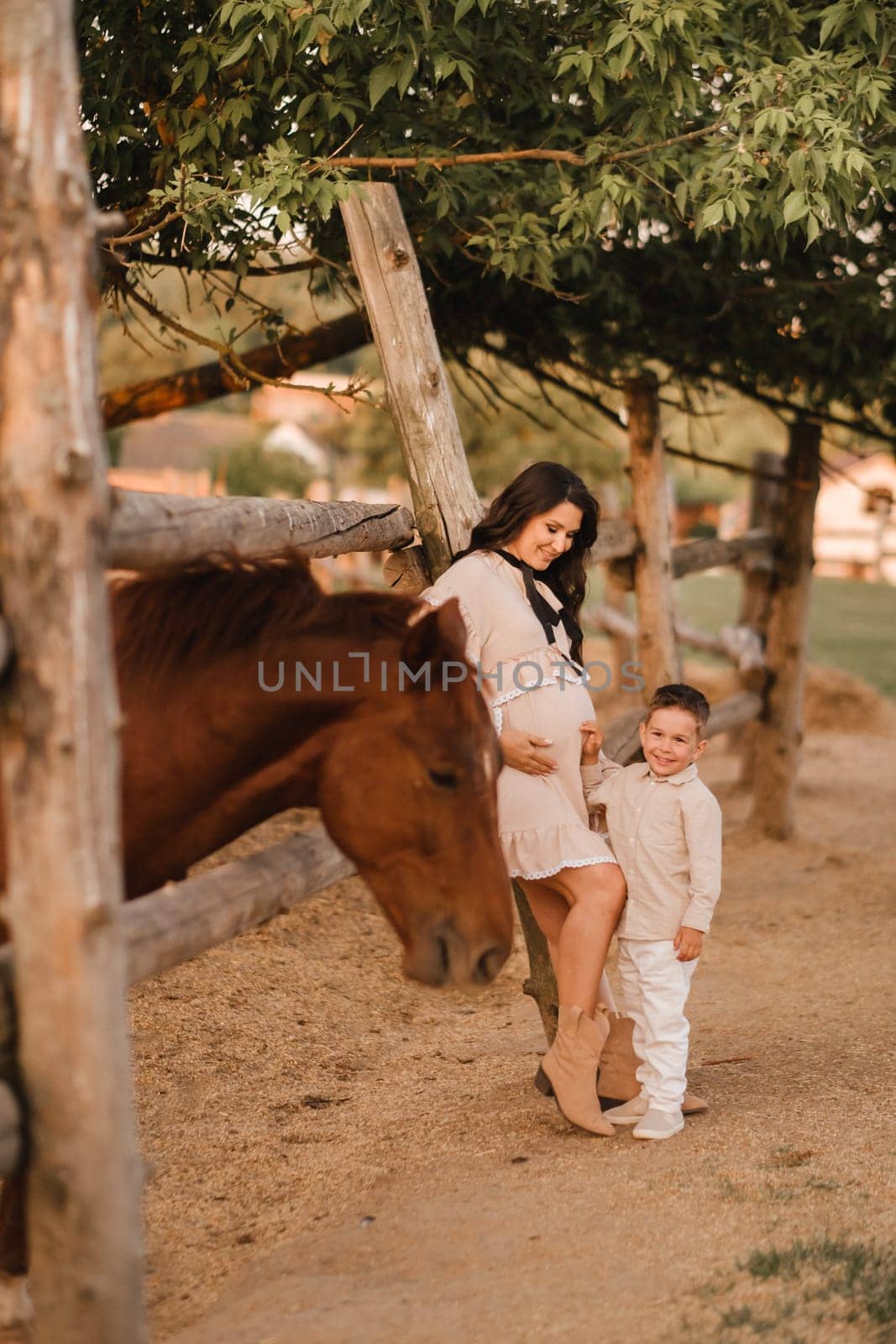 A pregnant woman with her son walks in the countryside in the summer.