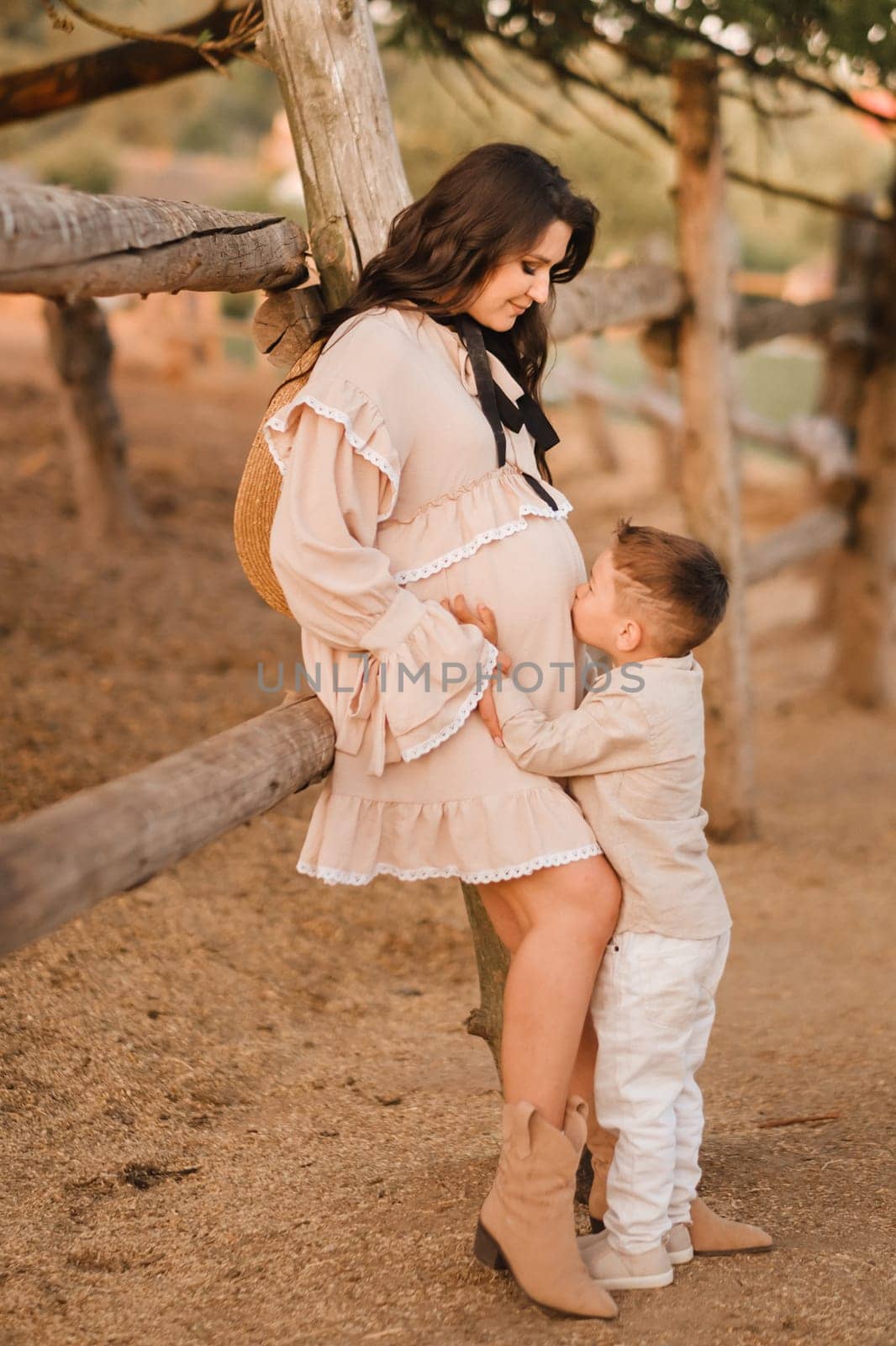 A pregnant woman with her son walks in the countryside in the summer.