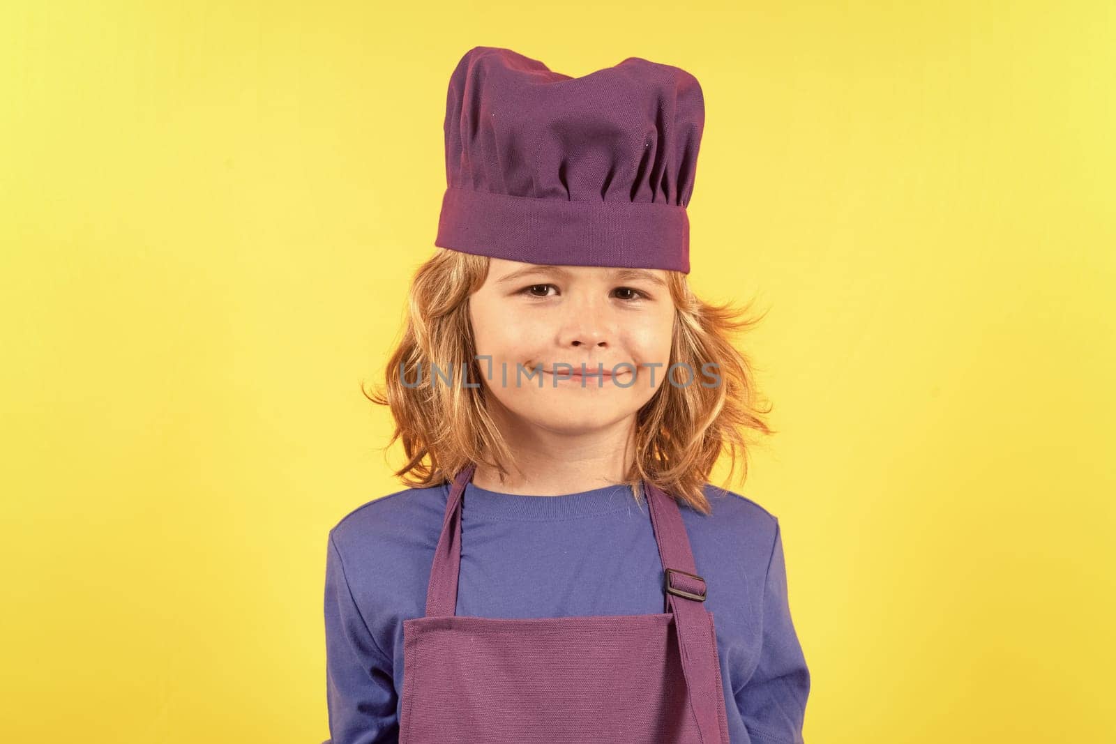 Funny kid chef cook studio portrait. Cooking children. Chef kid boy in form of cook. Child boy with apron and chef hat preparing a healthy meal in the kitchen. Cooking process