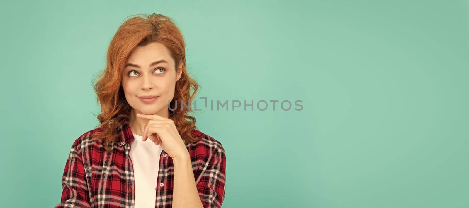 thinking redhead woman with curly hair in checkered casual shirt, thoughtful. Woman isolated face portrait, banner with mock up copyspace