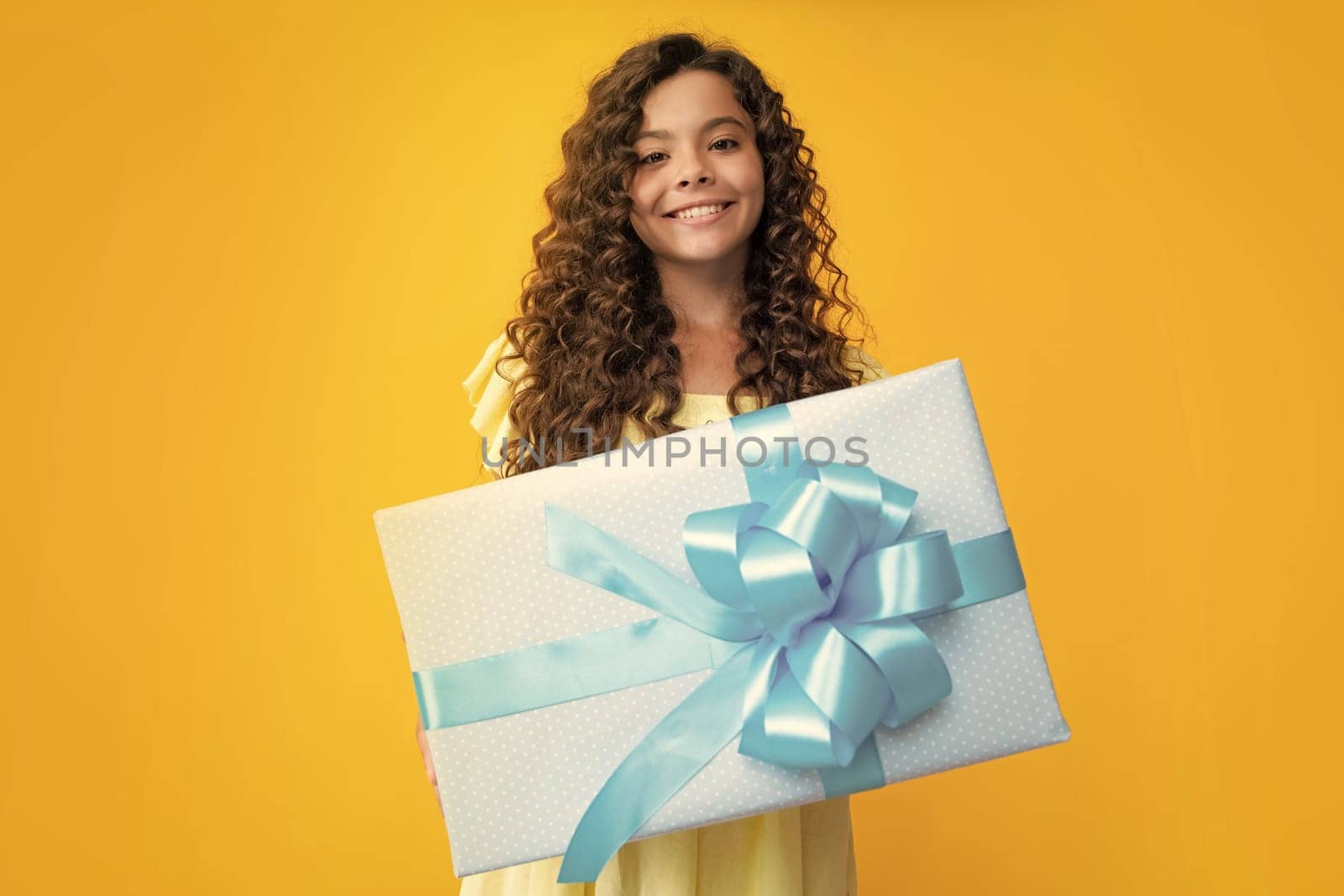 Happy teenager portrait. Child with gift present box on isolated background. Presents for birthday, Valentines day, New Year or Christmas. Smiling girl