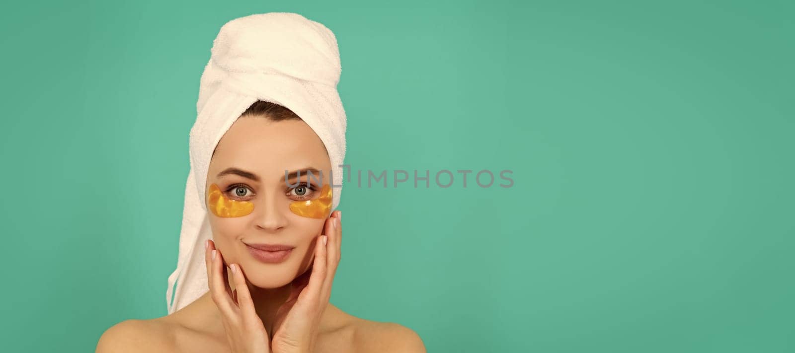 Eye patches, patch under eyes. smiling young girl has collagen golden eye patches on face with towel. Beautiful woman isolated face portrait, banner with mock up copy space