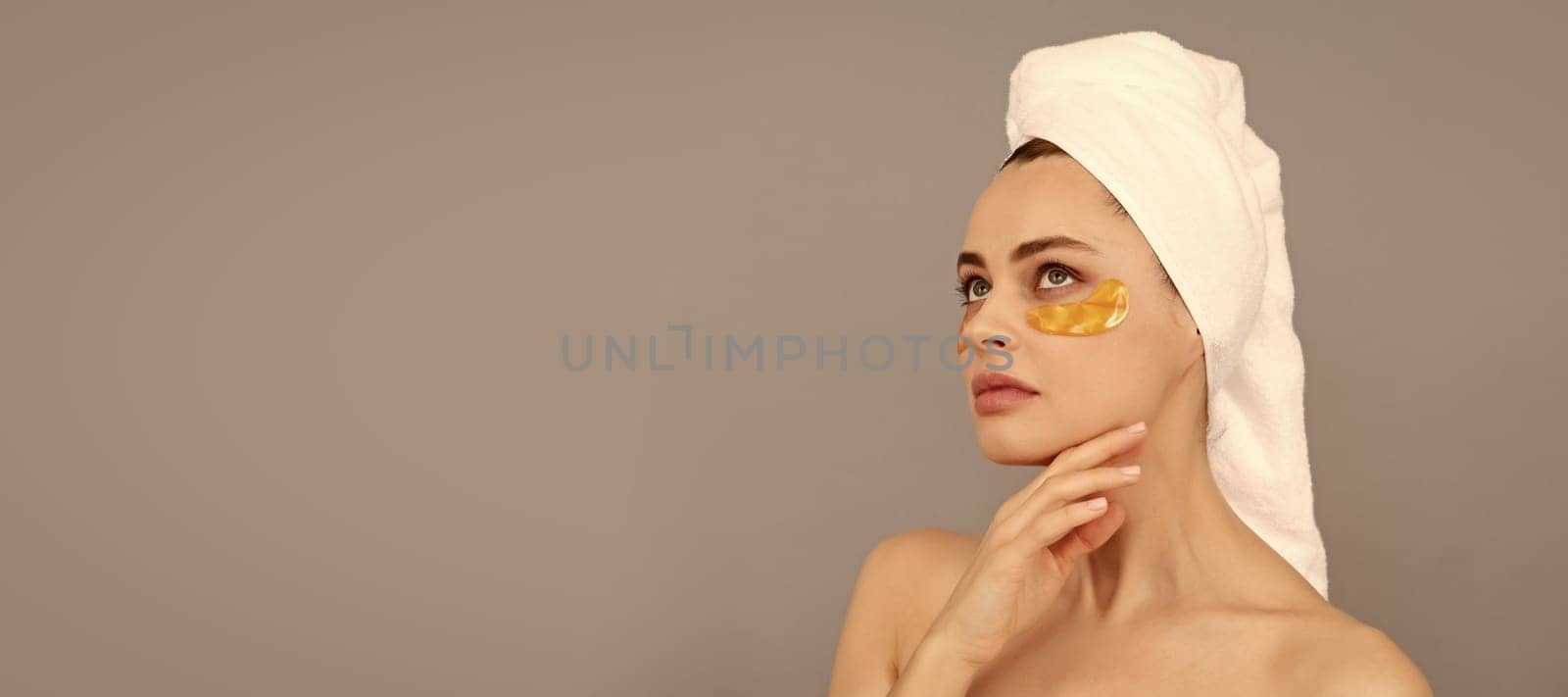 beautiful girl with terry towel use facial golden eye patch for skin, beauty. Beautiful woman isolated face portrait, banner with mock up copy space. by RedFoxStudio