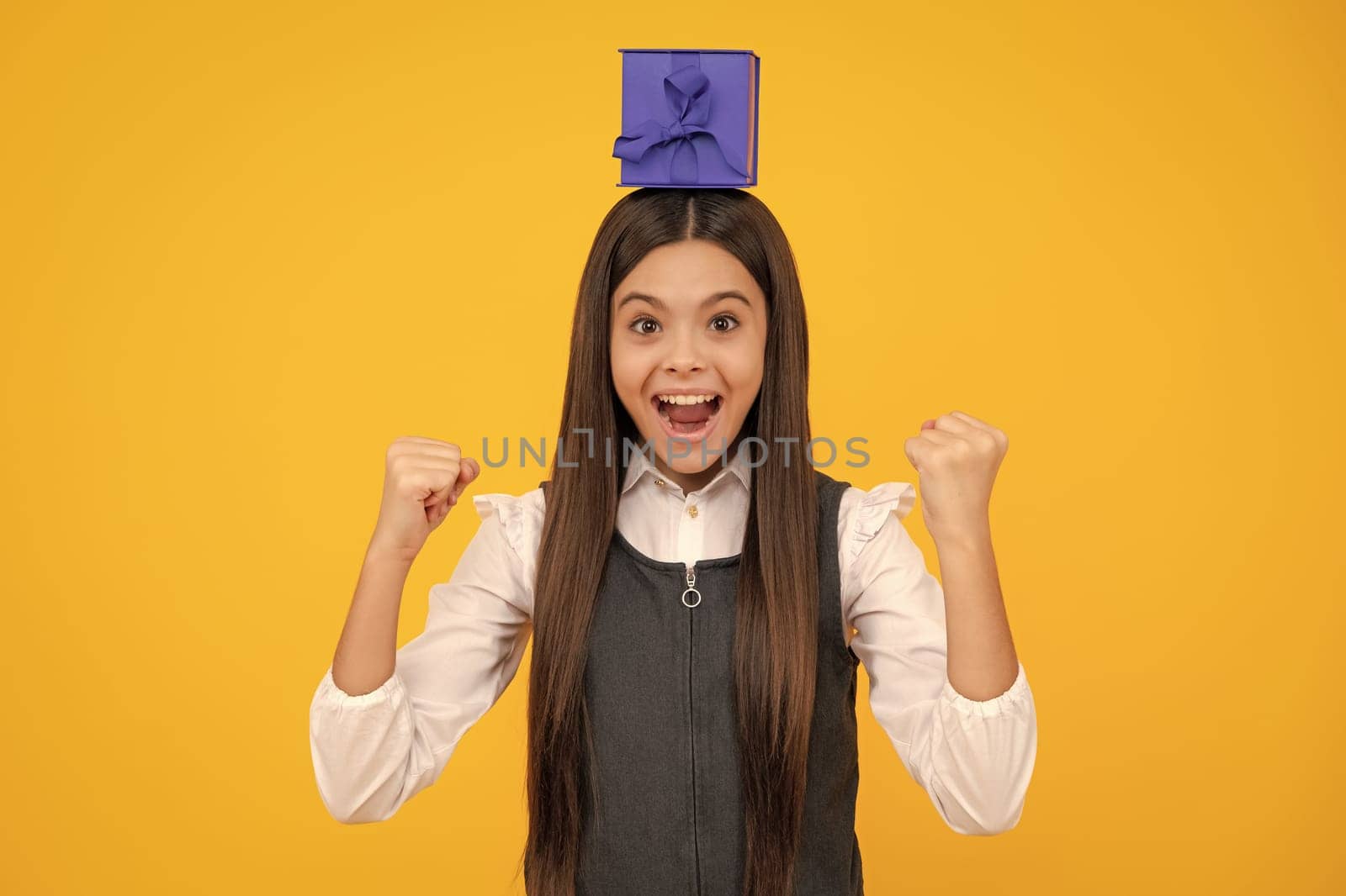 Amazed teen girl. Child with gift present box on isolated background. Presents for birthday, Valentines day, New Year or Christmas. Excited expression, cheerful and glad